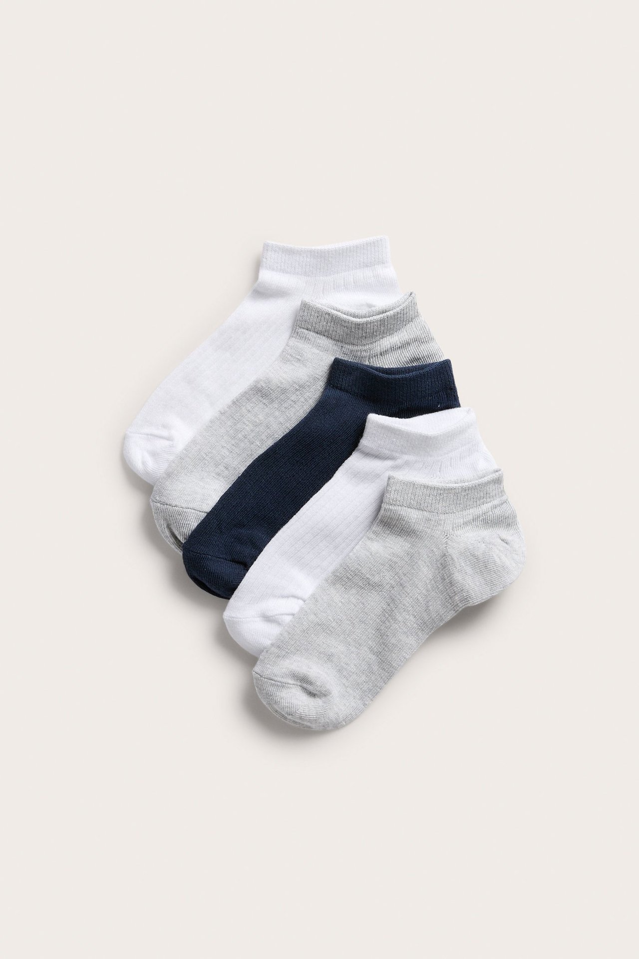 Widok z góry na pięć par prążkowanych skarpetek stopek w kolorze białym, jasnoszarym i granatowym.