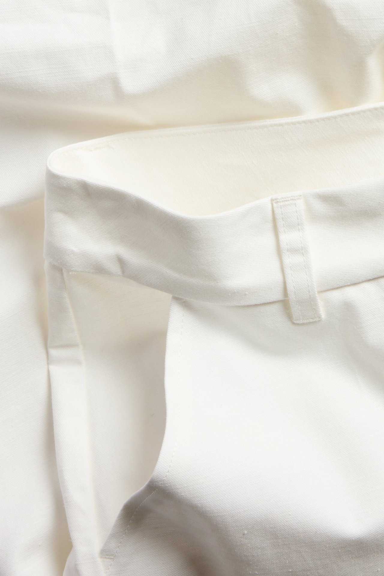 Zbliżenie białych szerokich spodni, pokazujące pas ze szlufką.