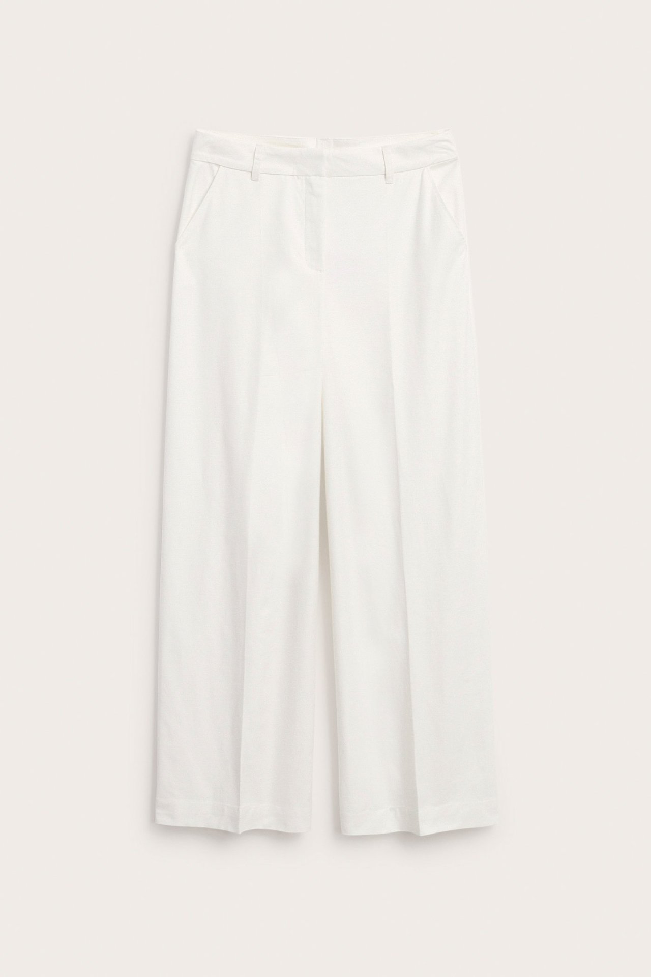 Edestä päin näkymä valkoisista leveälahkeisista housuista, joissa on prässit ja sivutaskut.