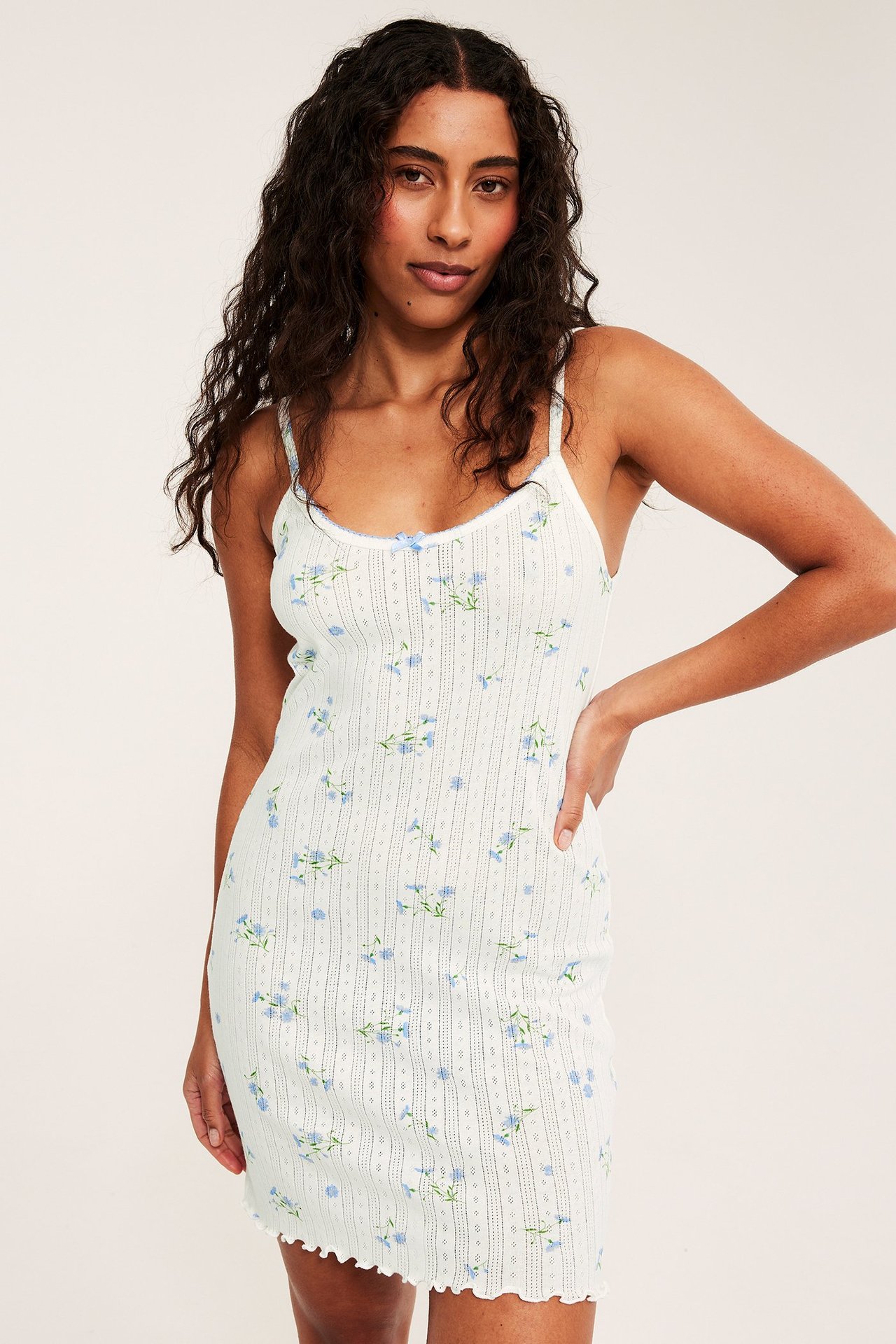 Widok z przodu: kobieta w jasnoniebieskiej bawełnianej koszuli nocnej pointelle w kwiaty i z koronką.