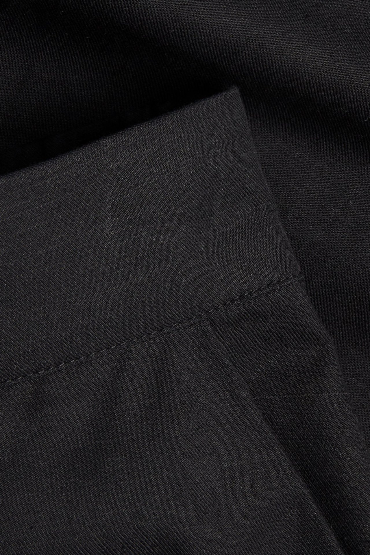 Närbild på svarta bermudashorts i bomullsmix, visar tygets struktur och sömmar.