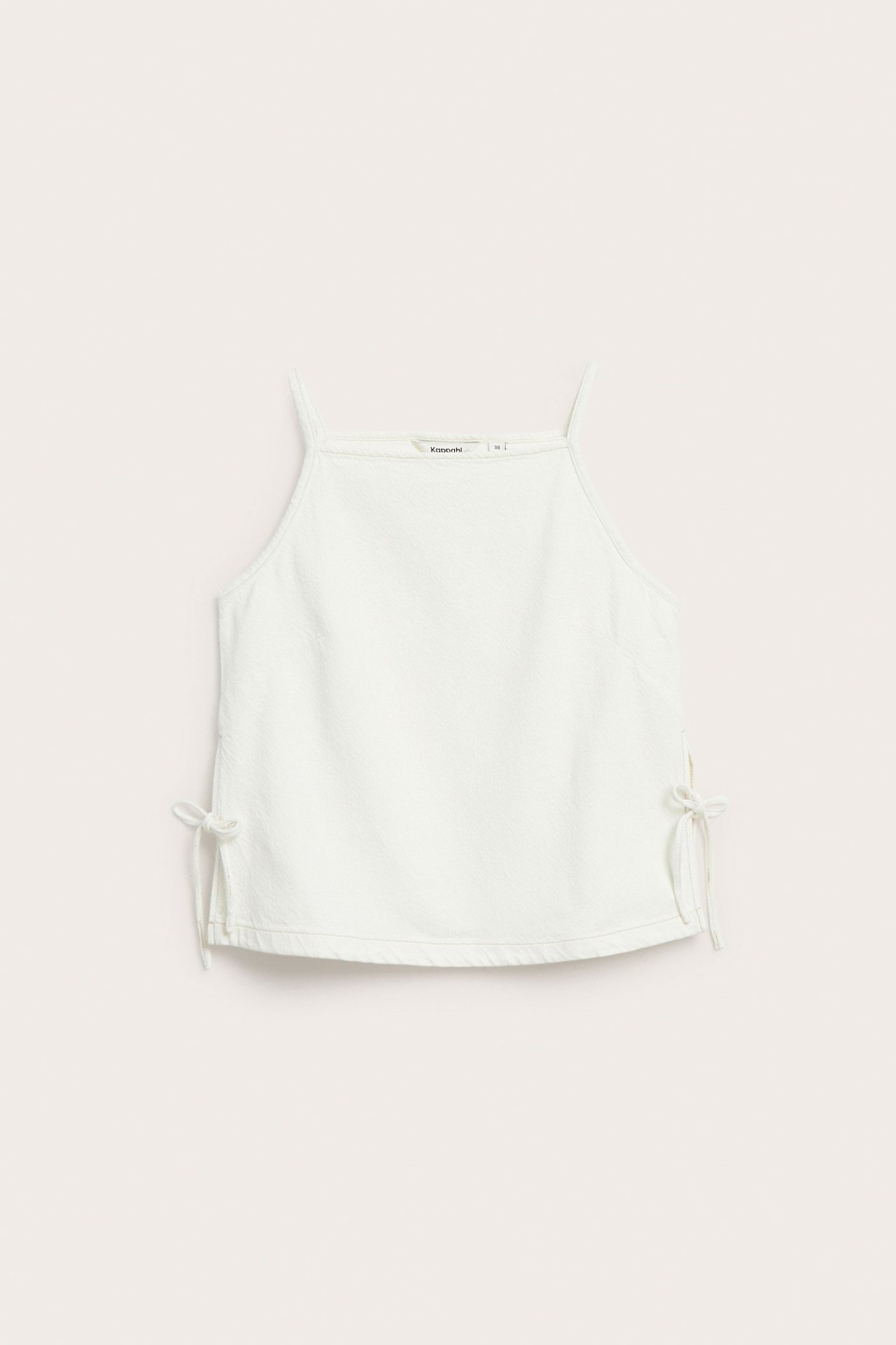 Frontvisning av offwhite bomullstopp i twill med knyting i sidene.