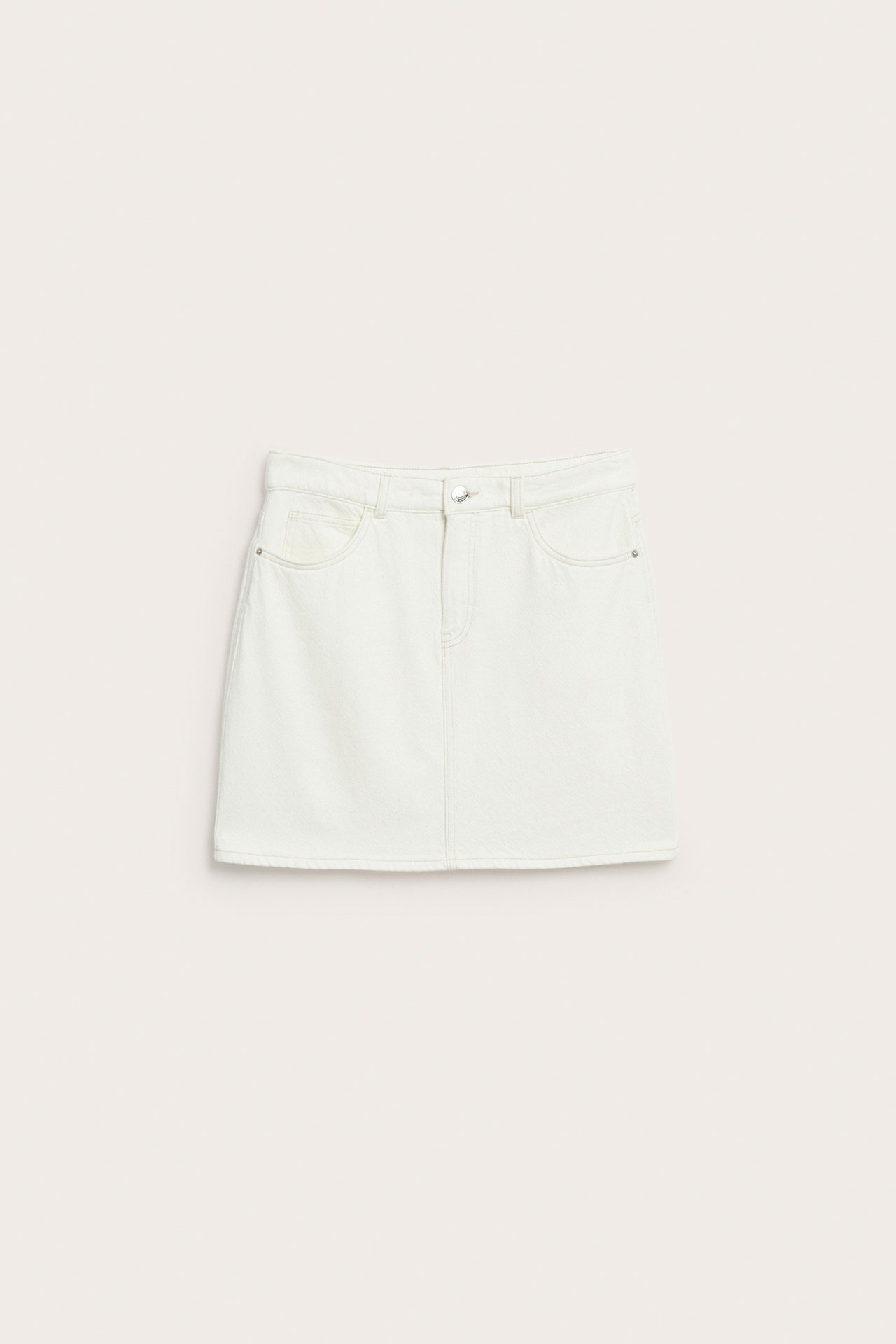 Forfra, kort offwhite bomullstwillskjørt med frontlommer, knapp og glidelås.