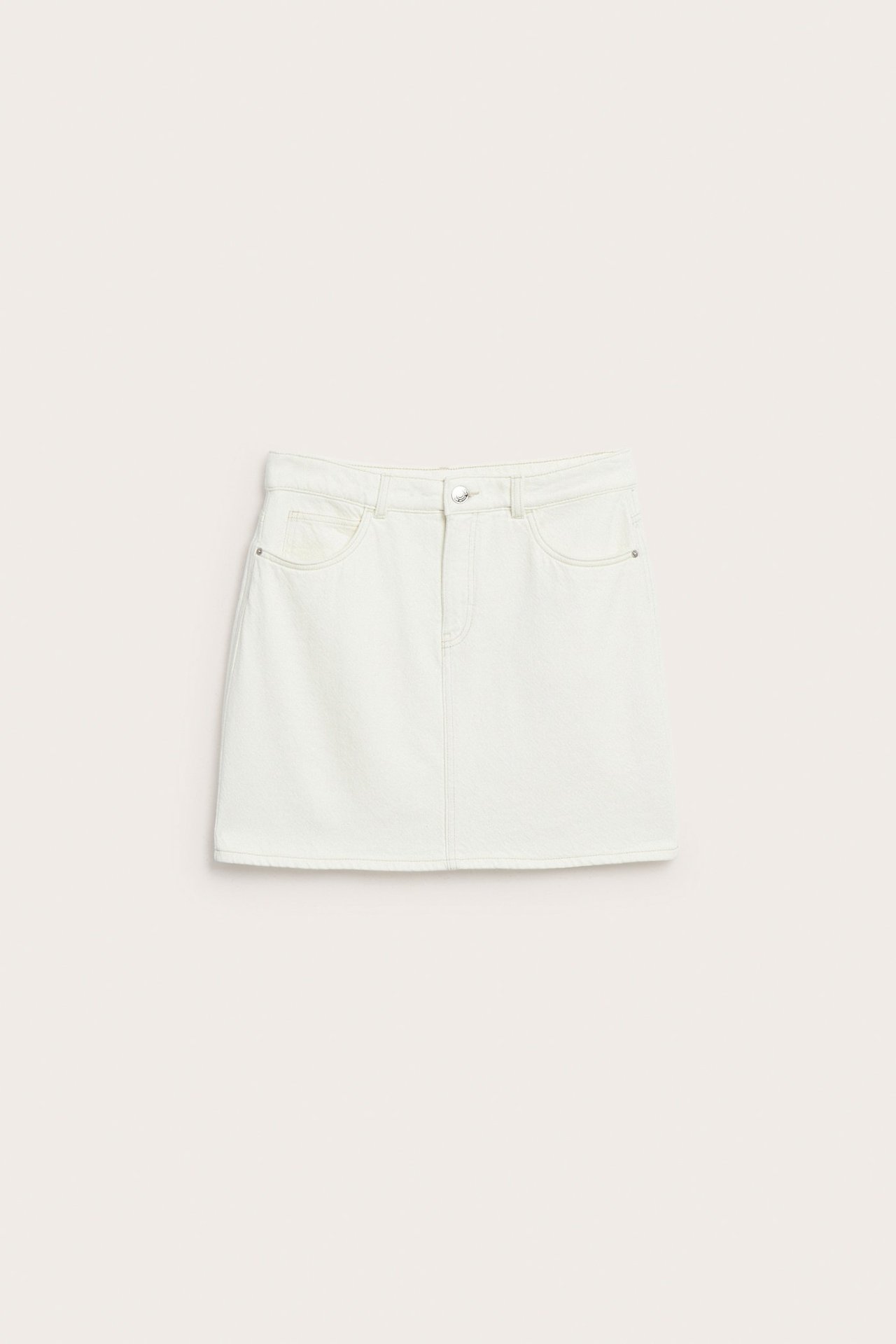 Forfra, kort offwhite bomullstwillskjørt med frontlommer, knapp og glidelås.