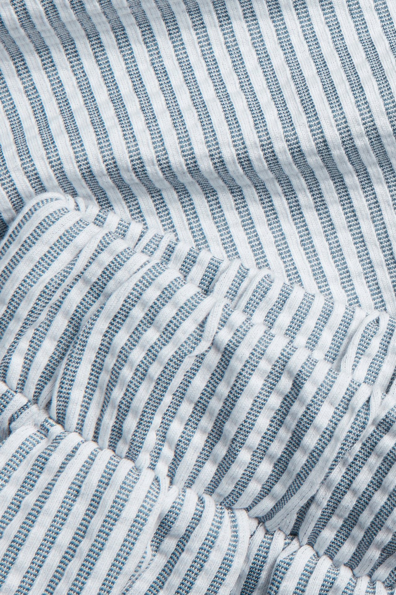 Zbliżenie na granatowo-białe pasiaste szorty piżamowe z dżerseju seersucker z elastycznym detalem.