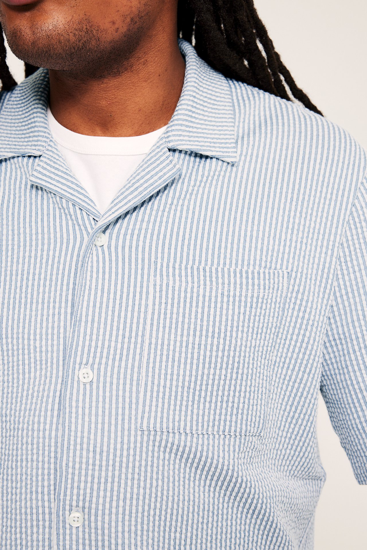 Z przodu: Męska niebiesko-biała koszula piżamowa z seersuckeru, kołnierzem resortowym, kieszenią, na białym t-shircie.
