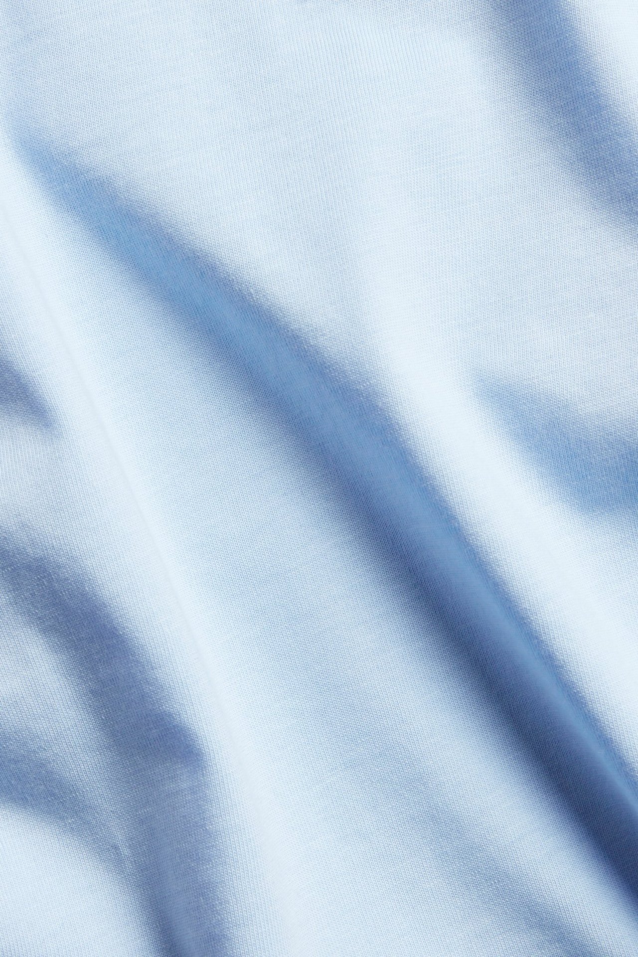 Zbliżenie na jasnoniebieską gładką tkaninę bawełnianą, część topu z bufiastymi rękawami.