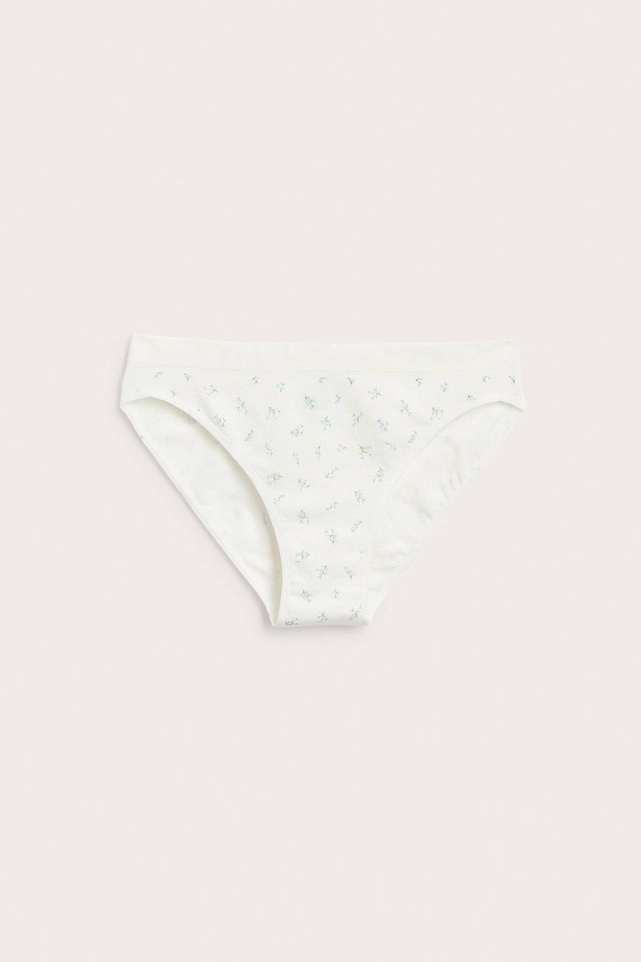 Edestäpäin, naisen valkoiset pehmeät alushousut vaaleansinisellä kukkakuviolla ja resorivyötäröllä.