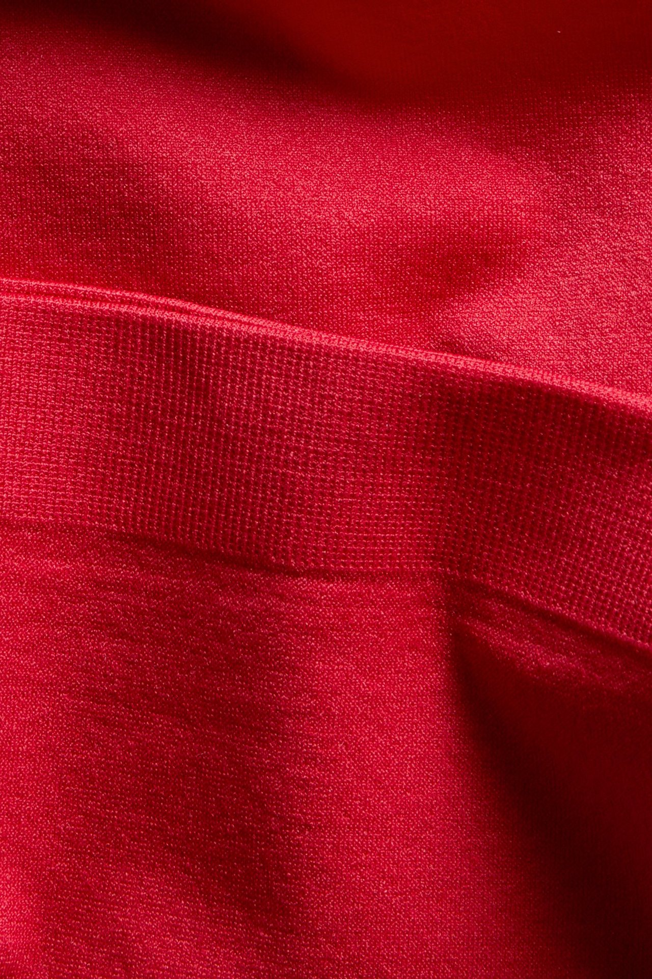 Lähikuva punaisista alushousuista ribatulla vyötäröllä pehmeää kangasta.