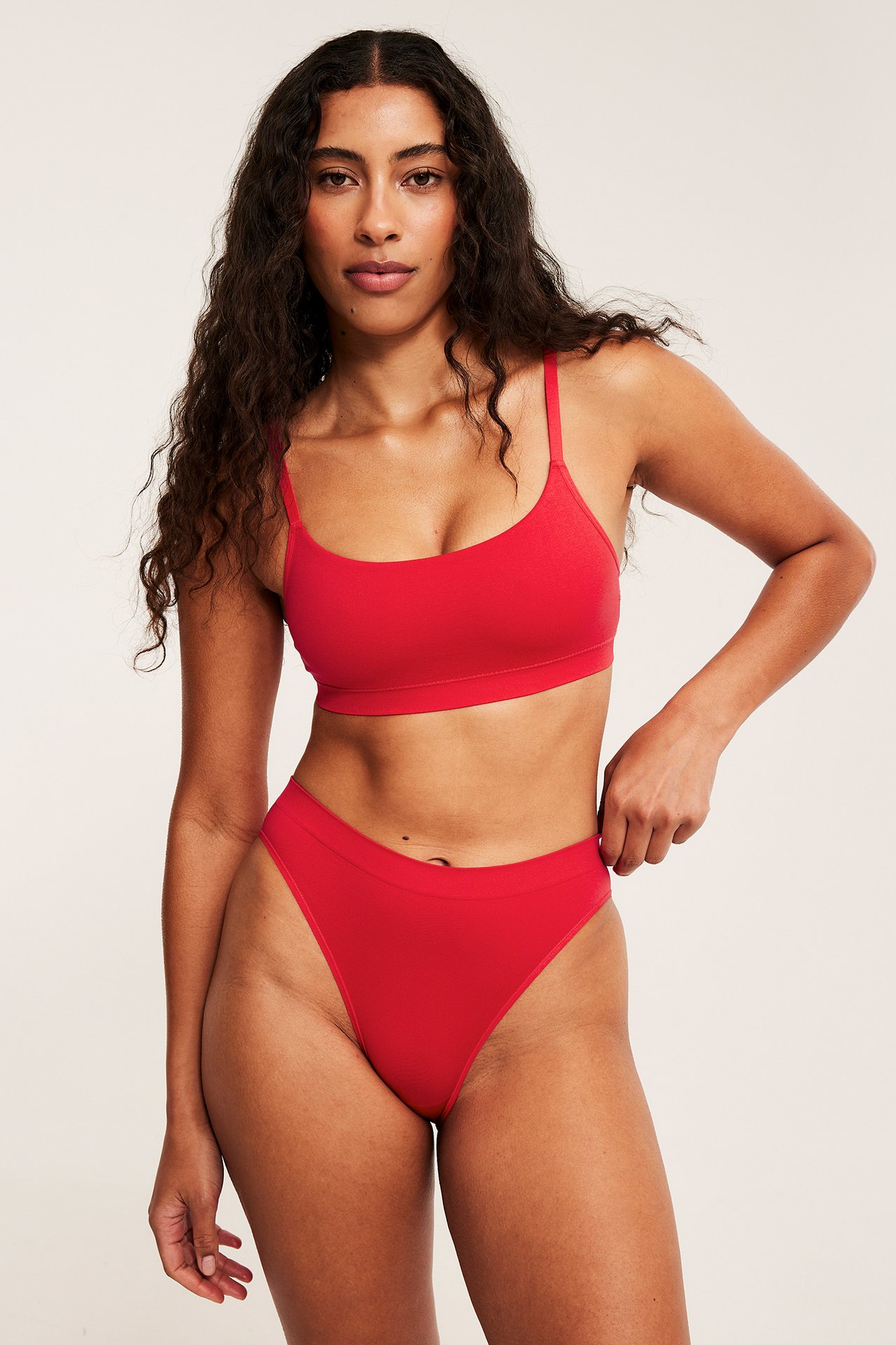 Framsida av kvinna i röda, mjuka trosor med ribbad midja, matchande röd bralette.