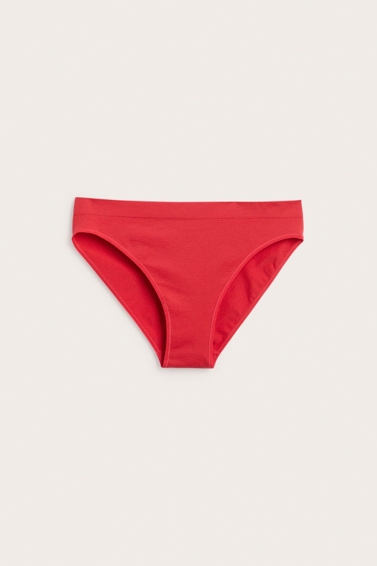 Edestäpäin näkymä punaisista, yksivärisistä alushousuista, joissa on ribattu vyötärö.