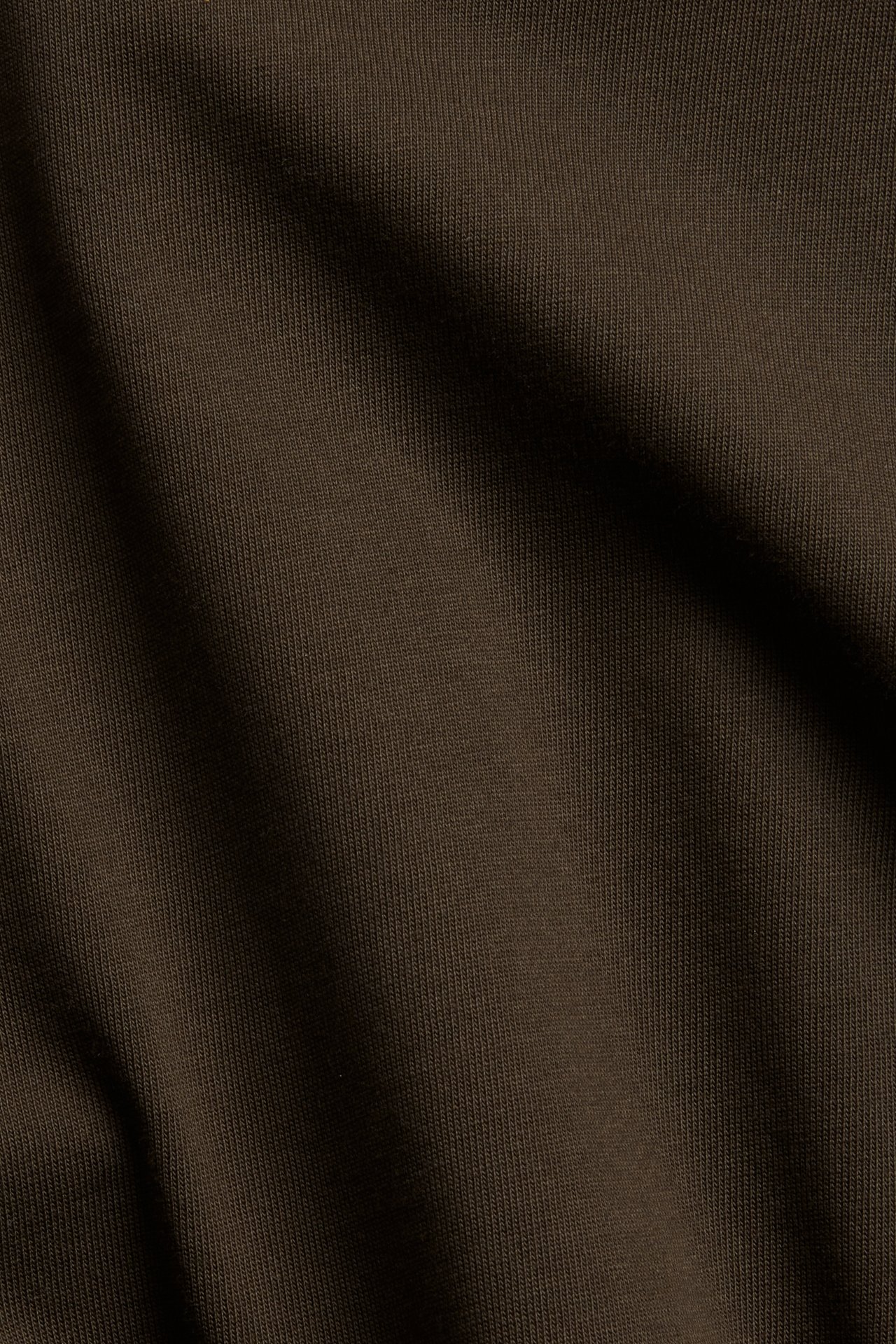 Nærbilde av et mørkebrunt ribbet bomullsstoff, egnet for en løstsittende T-skjorte.
