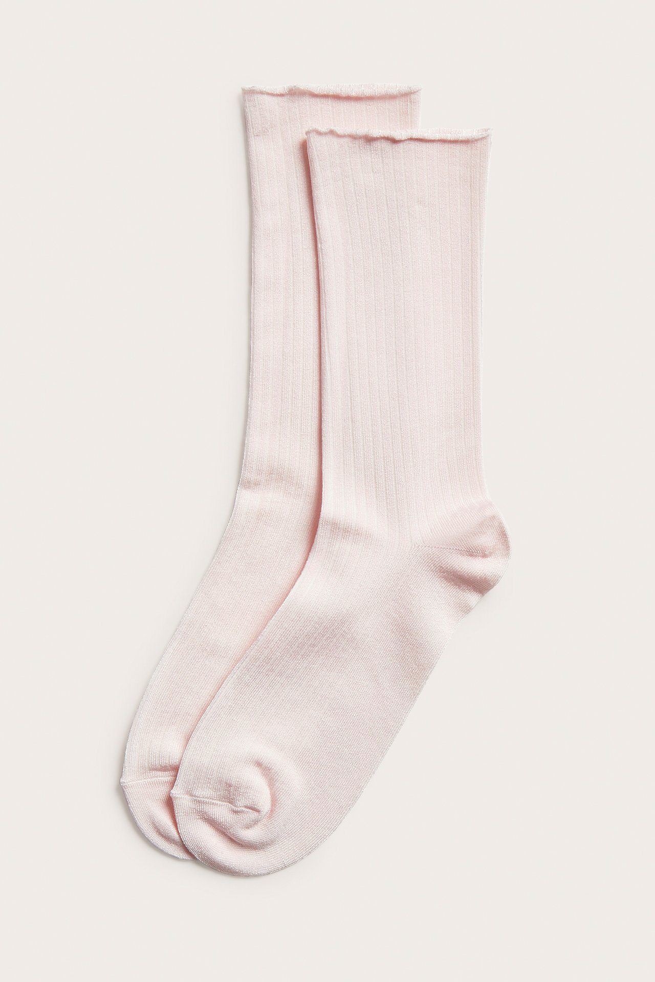 Edestä, pari vaaleanpunaisia ribattuja kiiltäviä sukkia, joissa rullareuna, tasaisesti aseteltuna.