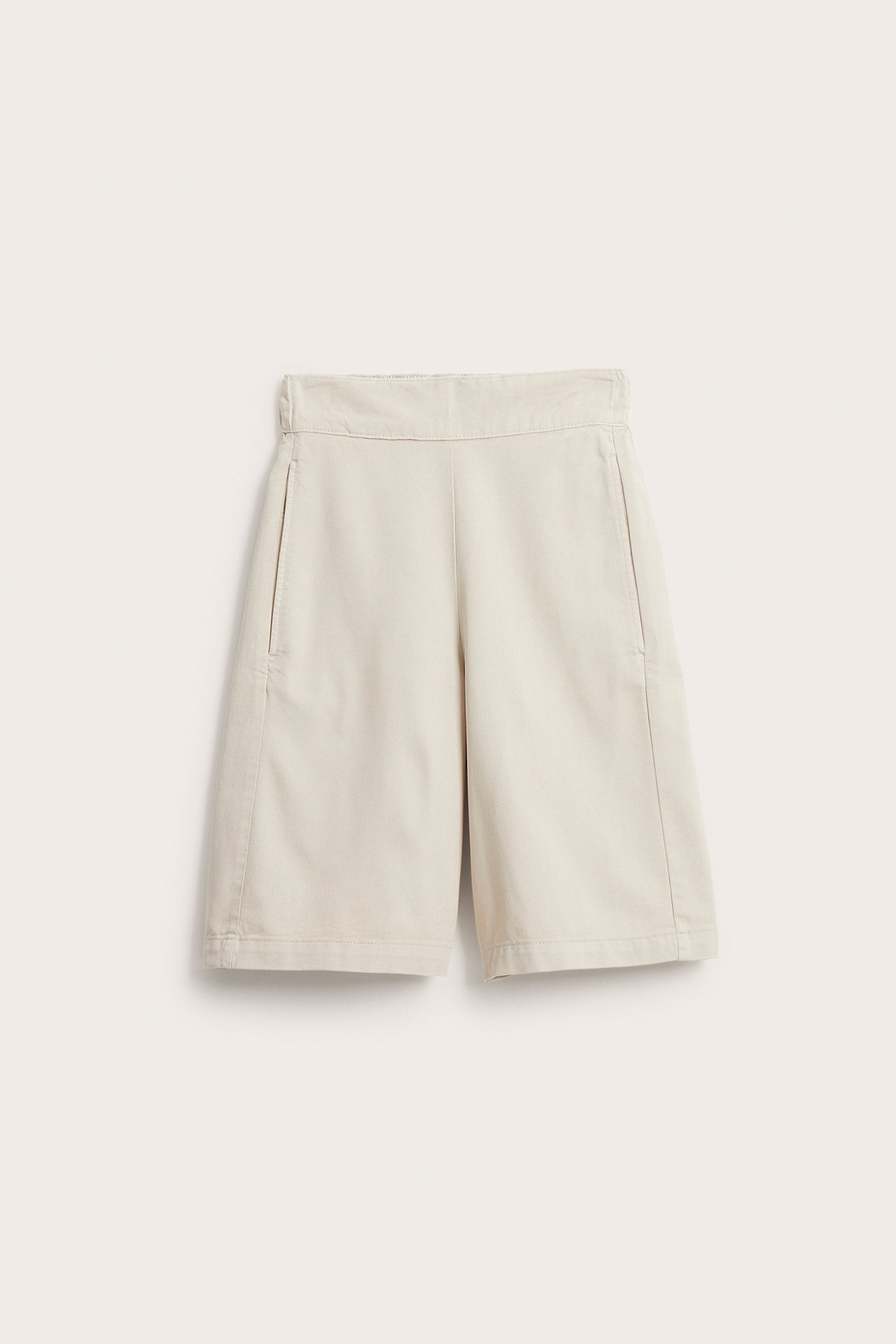 Edestä näkymä vaaleabeigeistä puuvillasekoite-bermudahortseista, joissa on löysä malli ja sivutaskut.