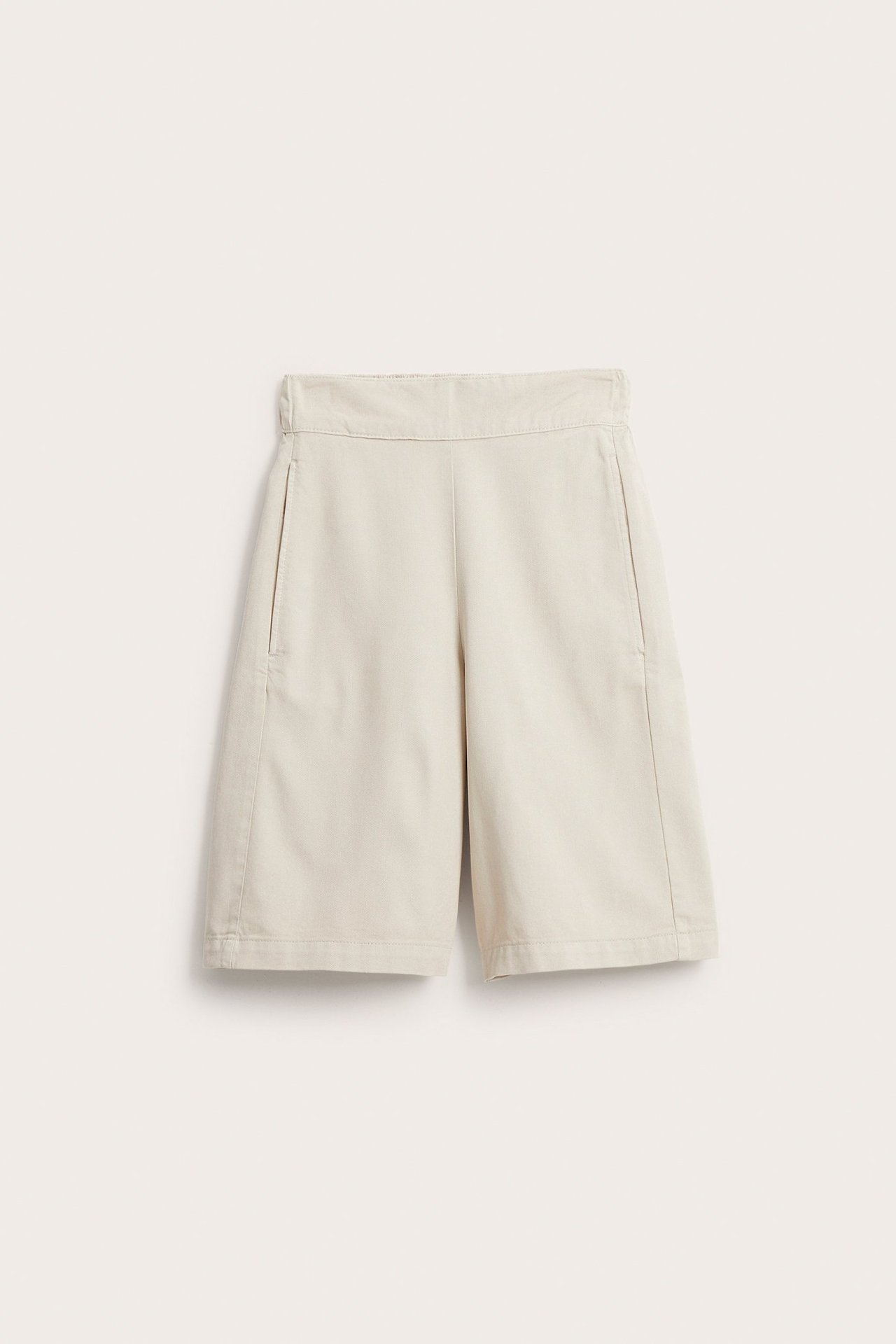 Edestä näkymä vaaleabeigeistä puuvillasekoite-bermudahortseista, joissa on löysä malli ja sivutaskut.