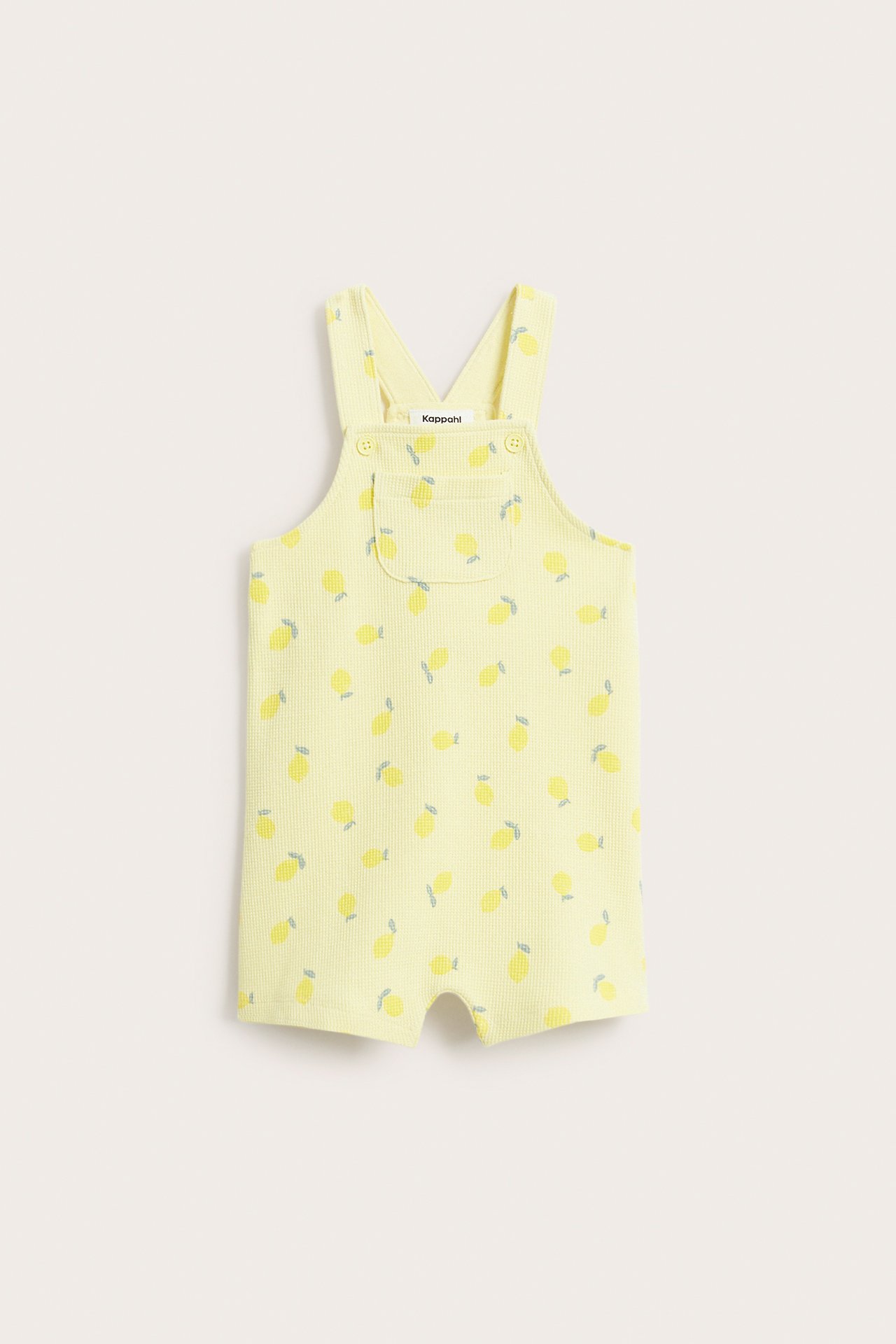 Widok z przodu jasnożółtych, waflowych ogrodniczek niemowlęcych z cytrynowym wzorem, kieszonką i guzikami z przodu.