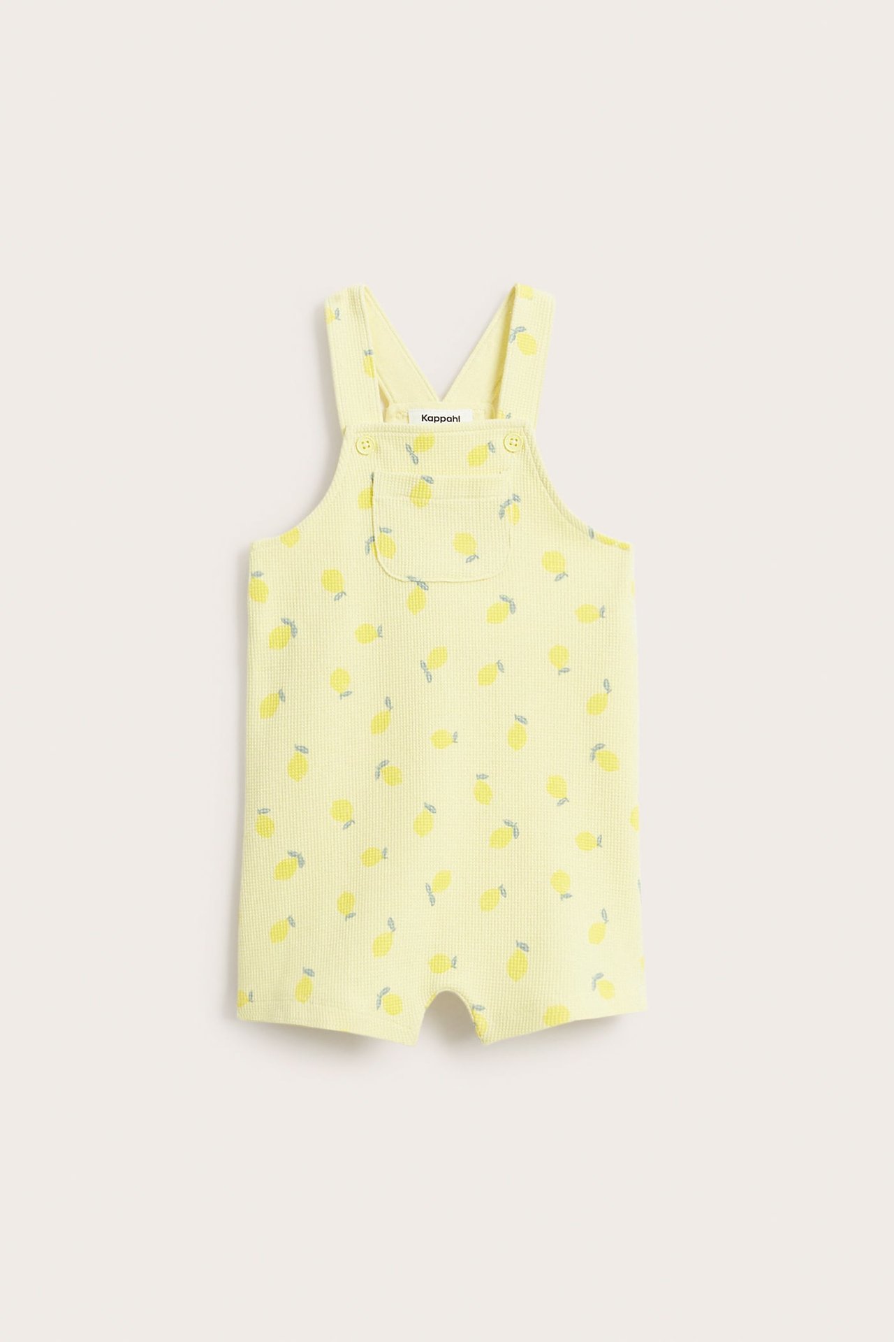 Frontvy av ljusgula hängselbyxor i våffelkvalitet för baby, med citronmönster, bröstficka och knappar fram.