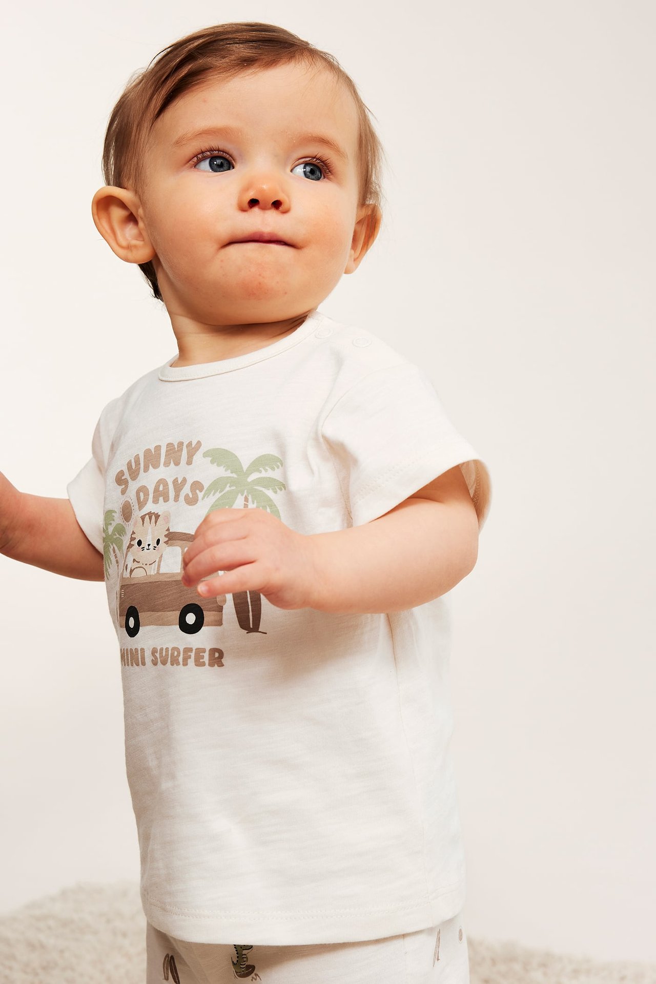 Vauva luonnonvalkoisessa jersey-T-paidassa 'Sunny Days' -printillä, olkapäänapit ja shortsit.