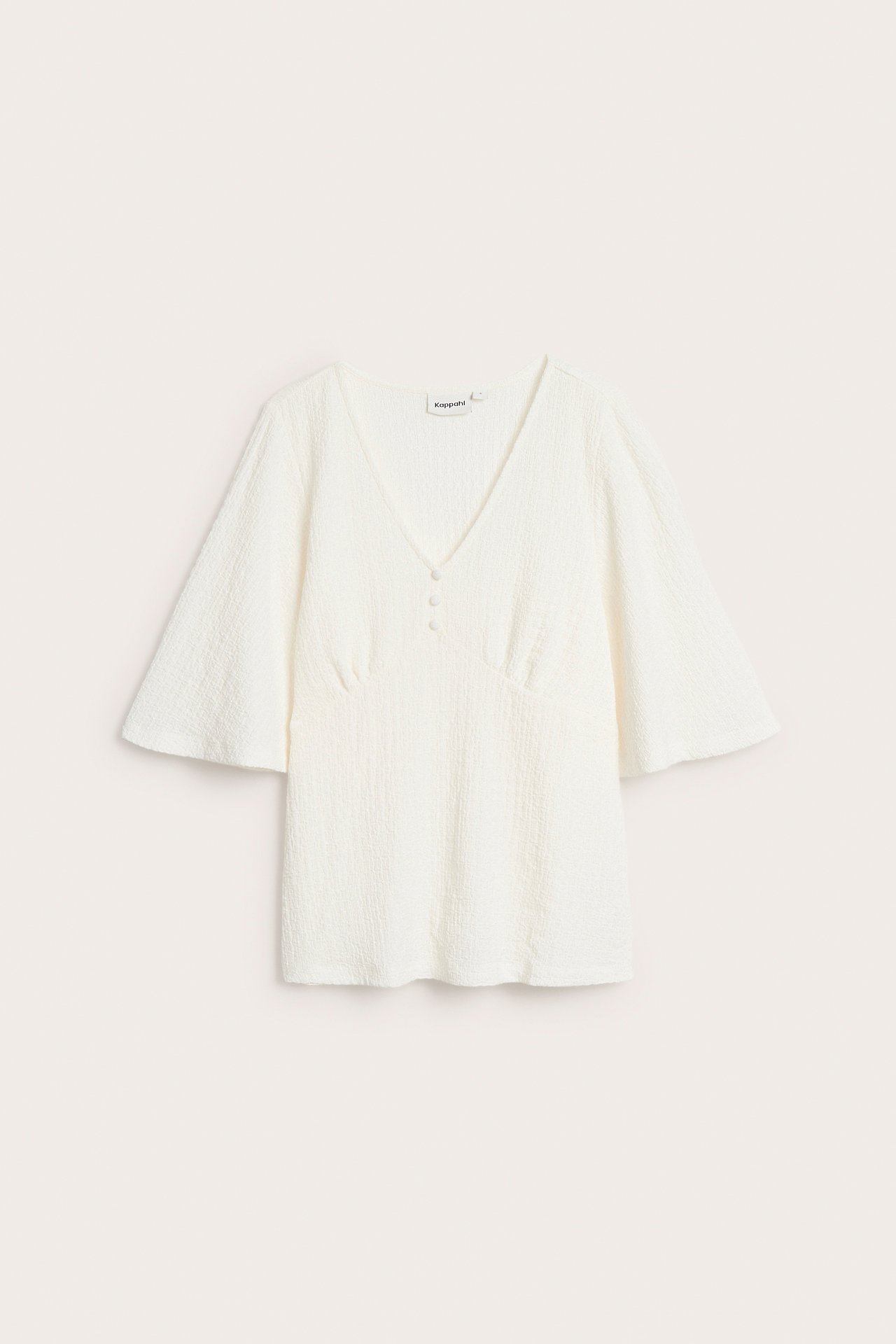 Edestäpäin, luonnonvalkoinen, kuvioitu lyhythihainen V-aukkoinen toppi, jossa leveät hihat ja kolme etunappia.