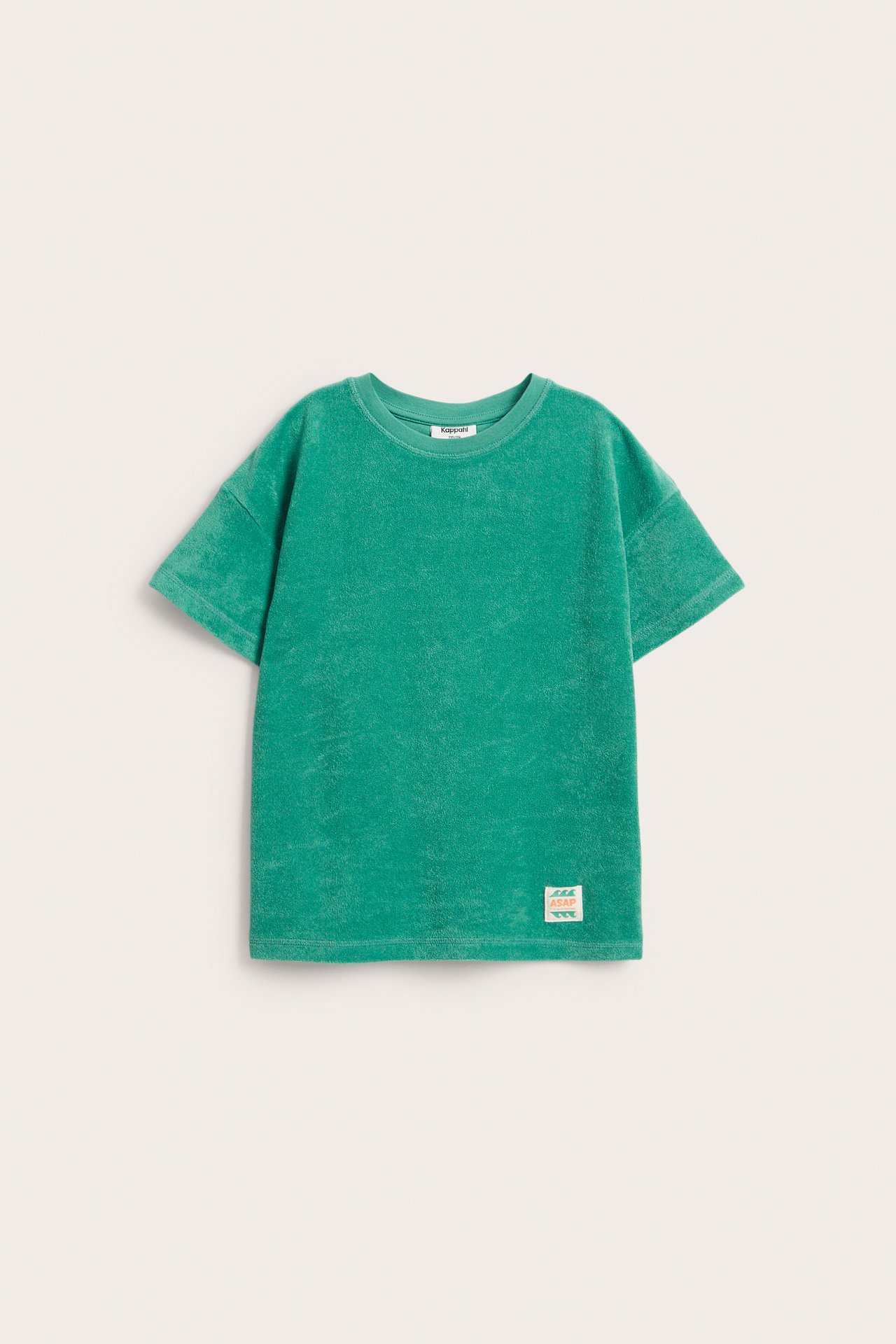 Framifrån: grön oversize frotté-t-shirt med droppade axlar och dekorativ patch.