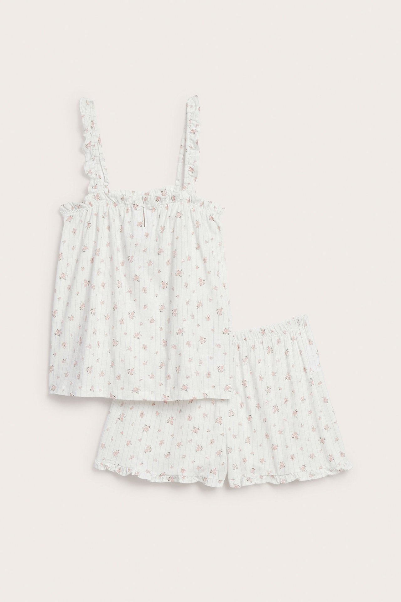 Edestä: naisten offwhite puuvillapyjama, vaaleanpunainen kukkakuvio, röyhelöt ja joustavat shortsit.