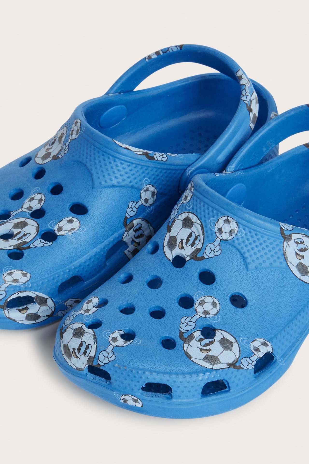 Zbliżenie z przodu na dwa niebieskie plastikowe klapki z wzorem piłki nożnej.