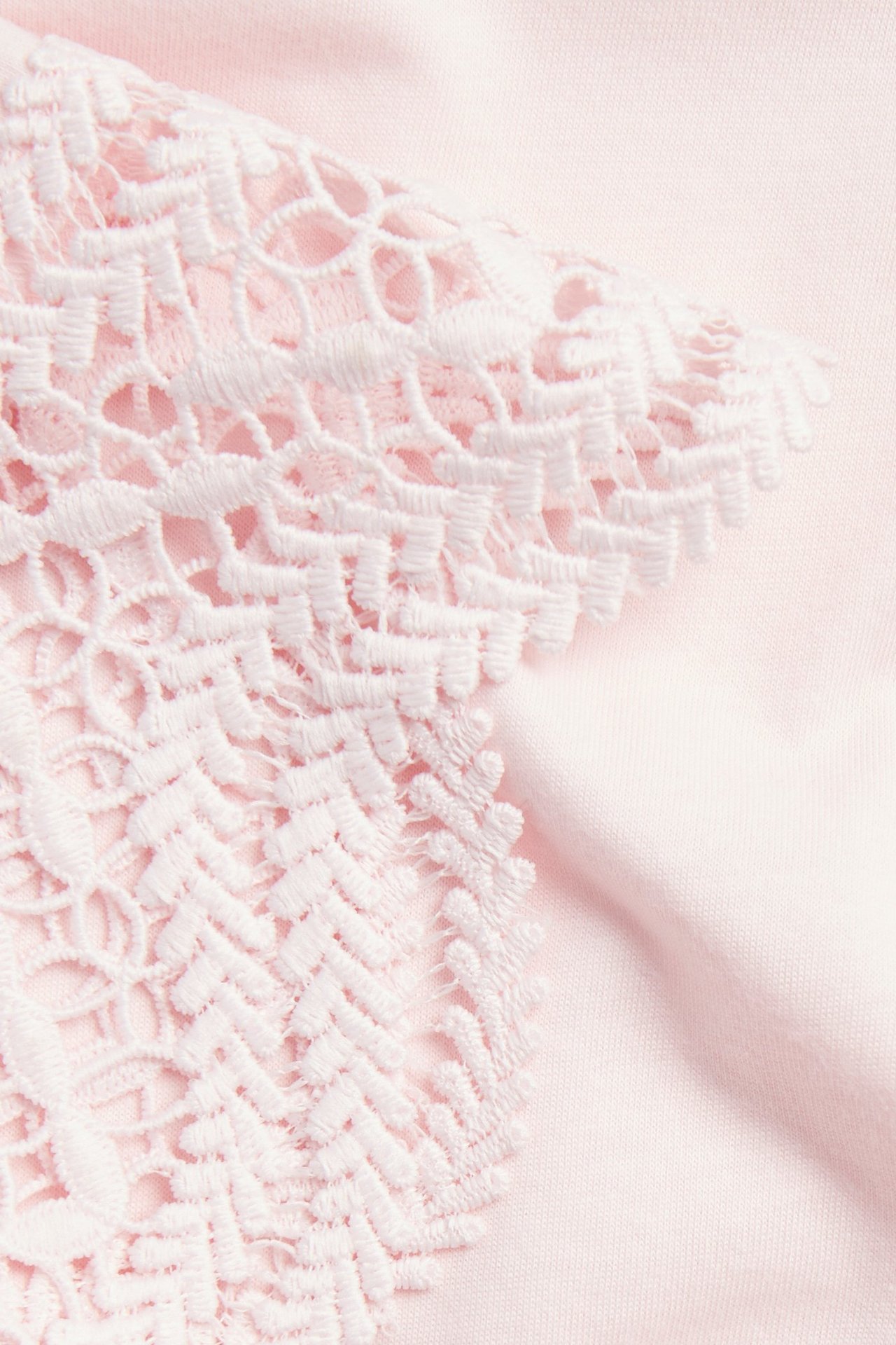 Nærbilde av en lys rosa t-skjorte med lys rosa blondedetaljer.