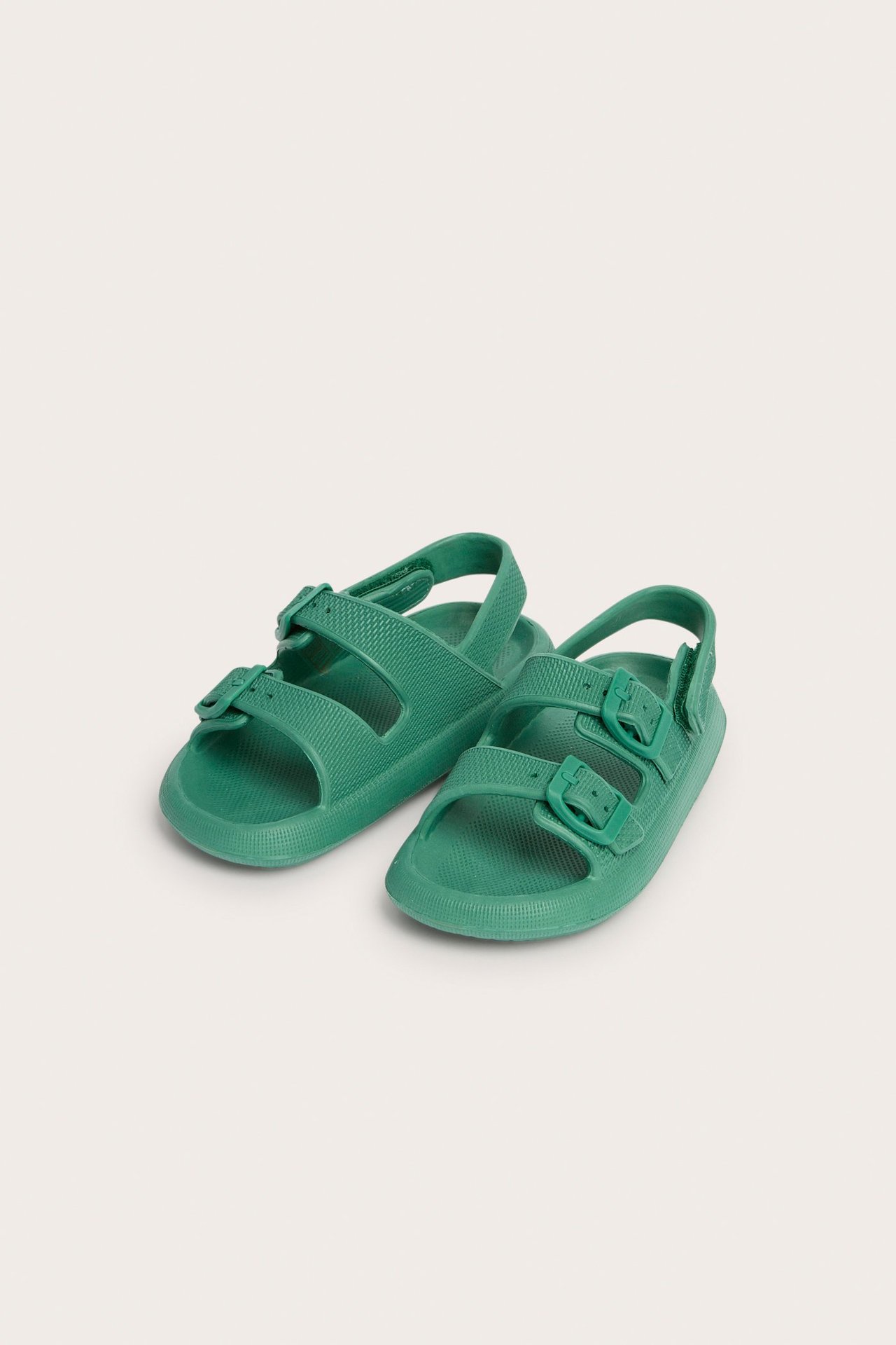 Edestä: vihreät muoviset lastensandaalit säädettävillä hihnoilla ja soljilla.