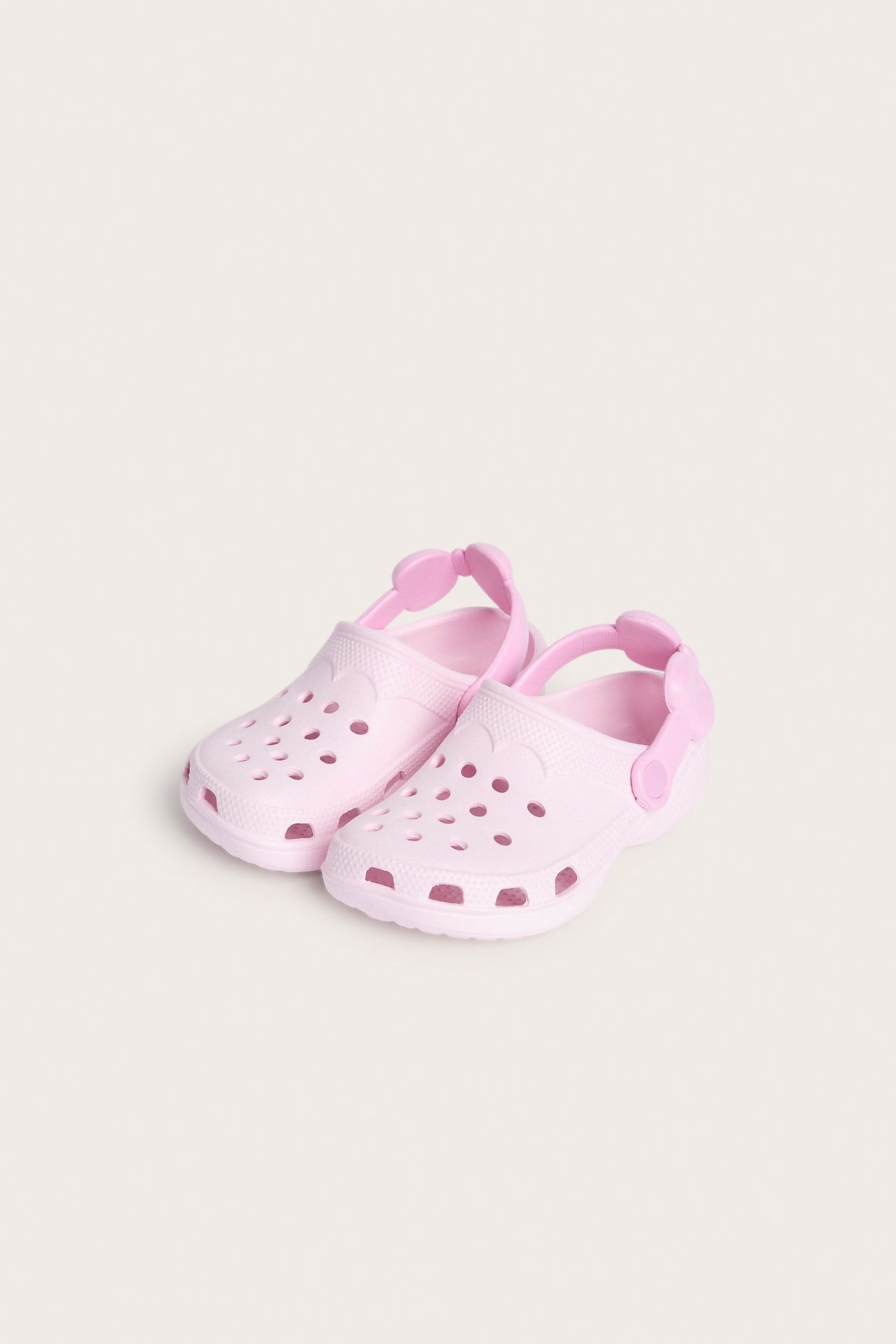 Widok z góry na jasnoróżowe plastikowe klapki z otworami wentylacyjnymi i paskami z kokardką.