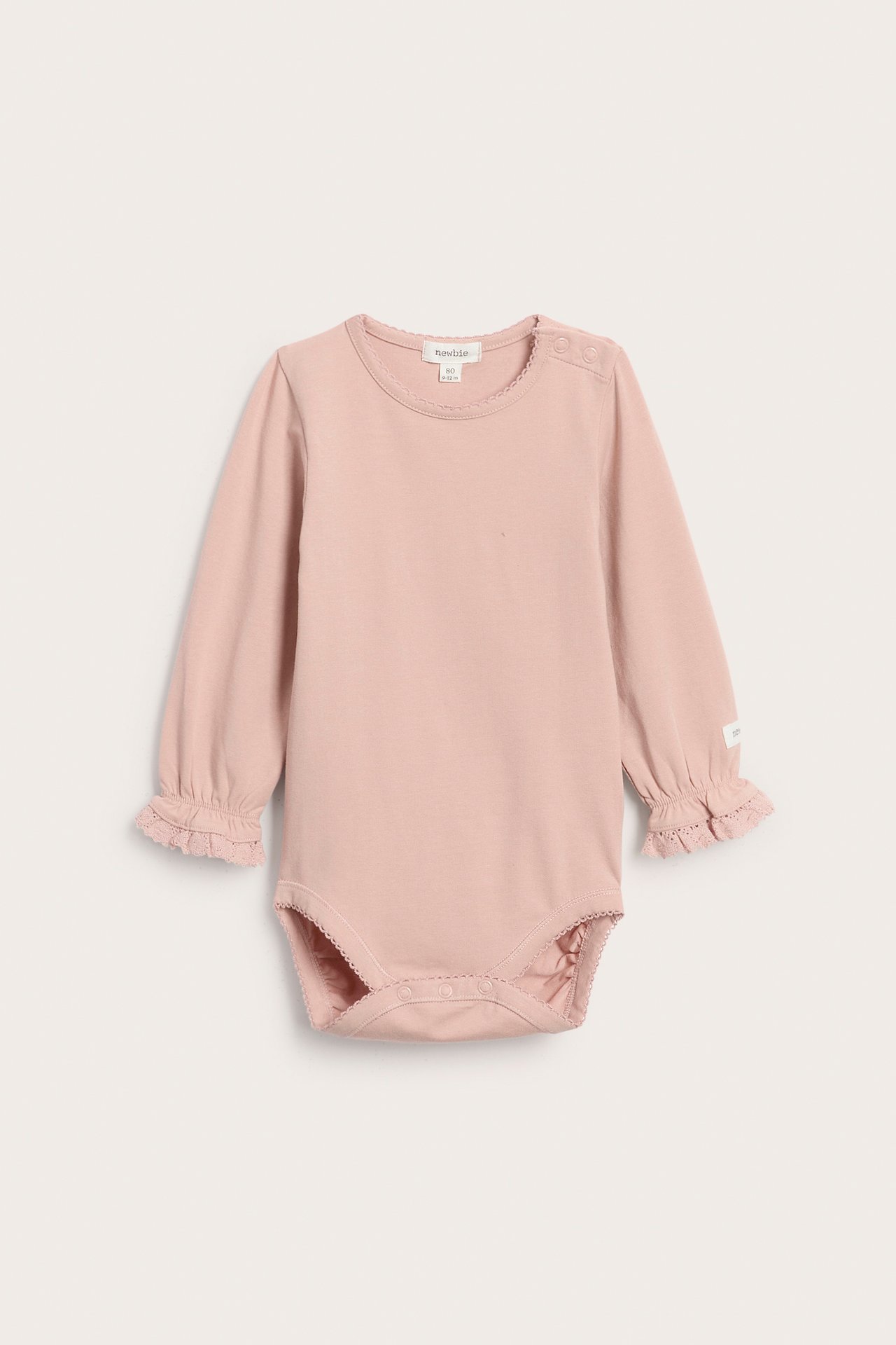 Framifrån: rosa långärmad babybody med spetsdetaljer och tryckknappar.