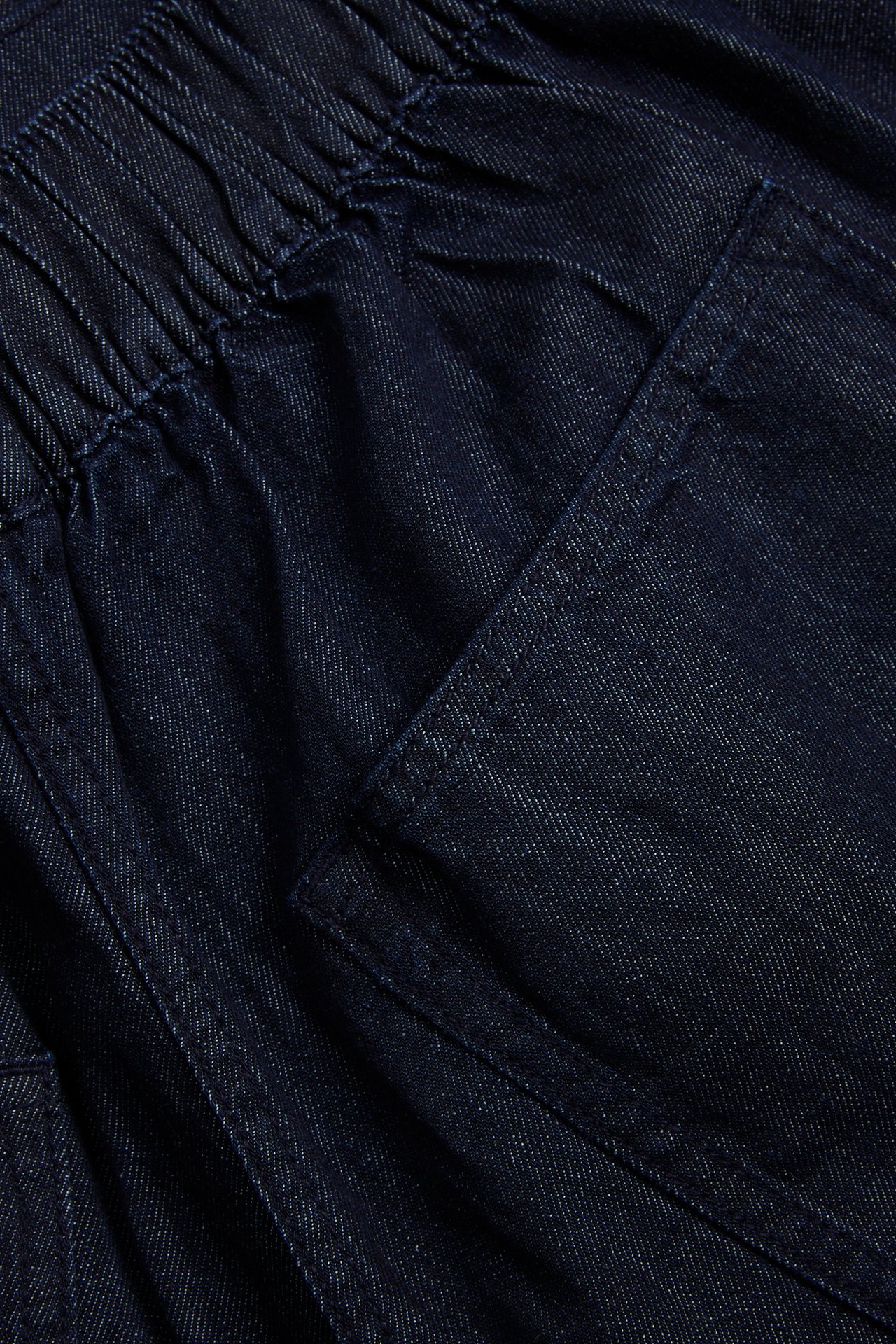 Nærbilde av mørkeblå denim culotte pull-on jeans med elastisk linning og en sidelomme.