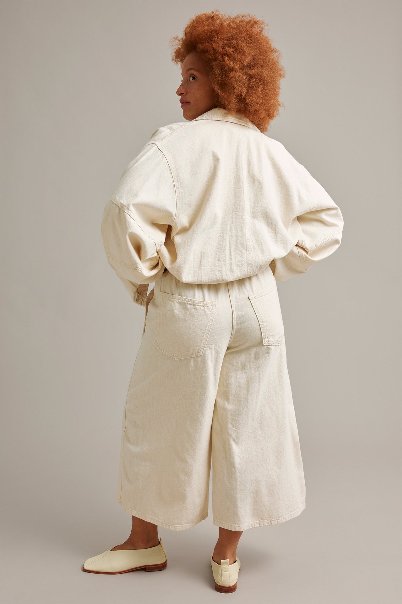 Bakside-sidevisning: Kvinne i beige pull-on culotte-jeans, en oversized beige jakke og lysebeige flate sko.
