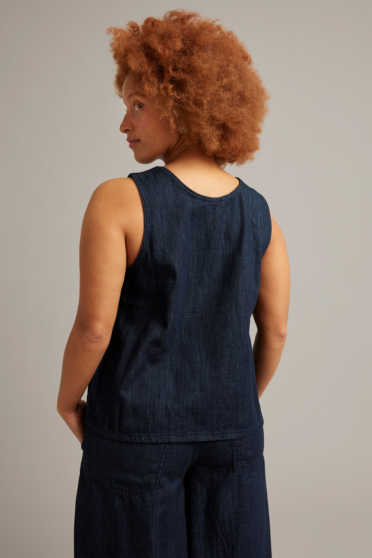 Baksidan av en kvinna i ett mörkt denimlinne och matchande mörka denimbyxor.