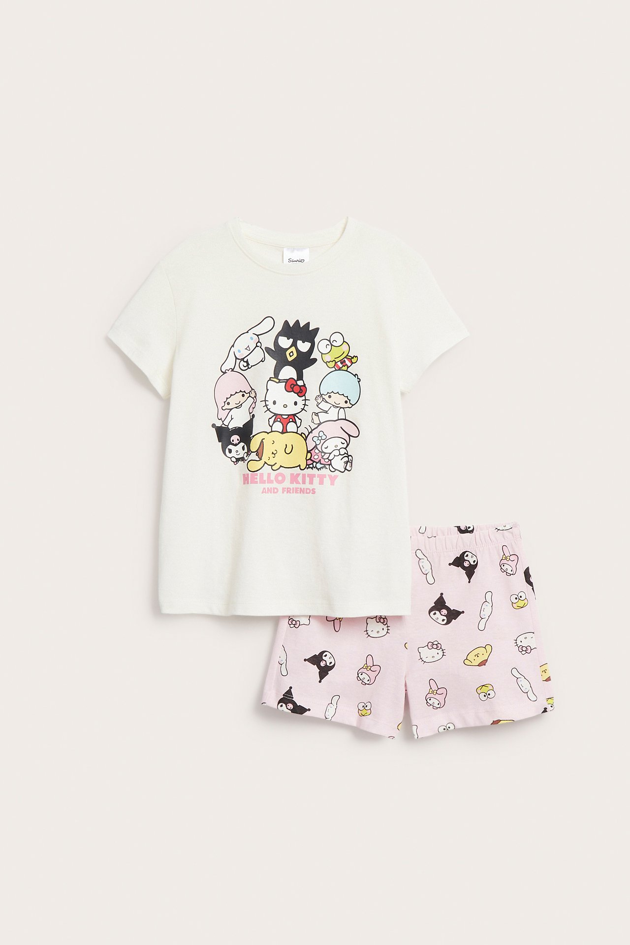 Framifrån: Vit barnpyjamas i bomull: Hello Kitty t-shirt med tryck och matchande rosa mönstrade shorts.