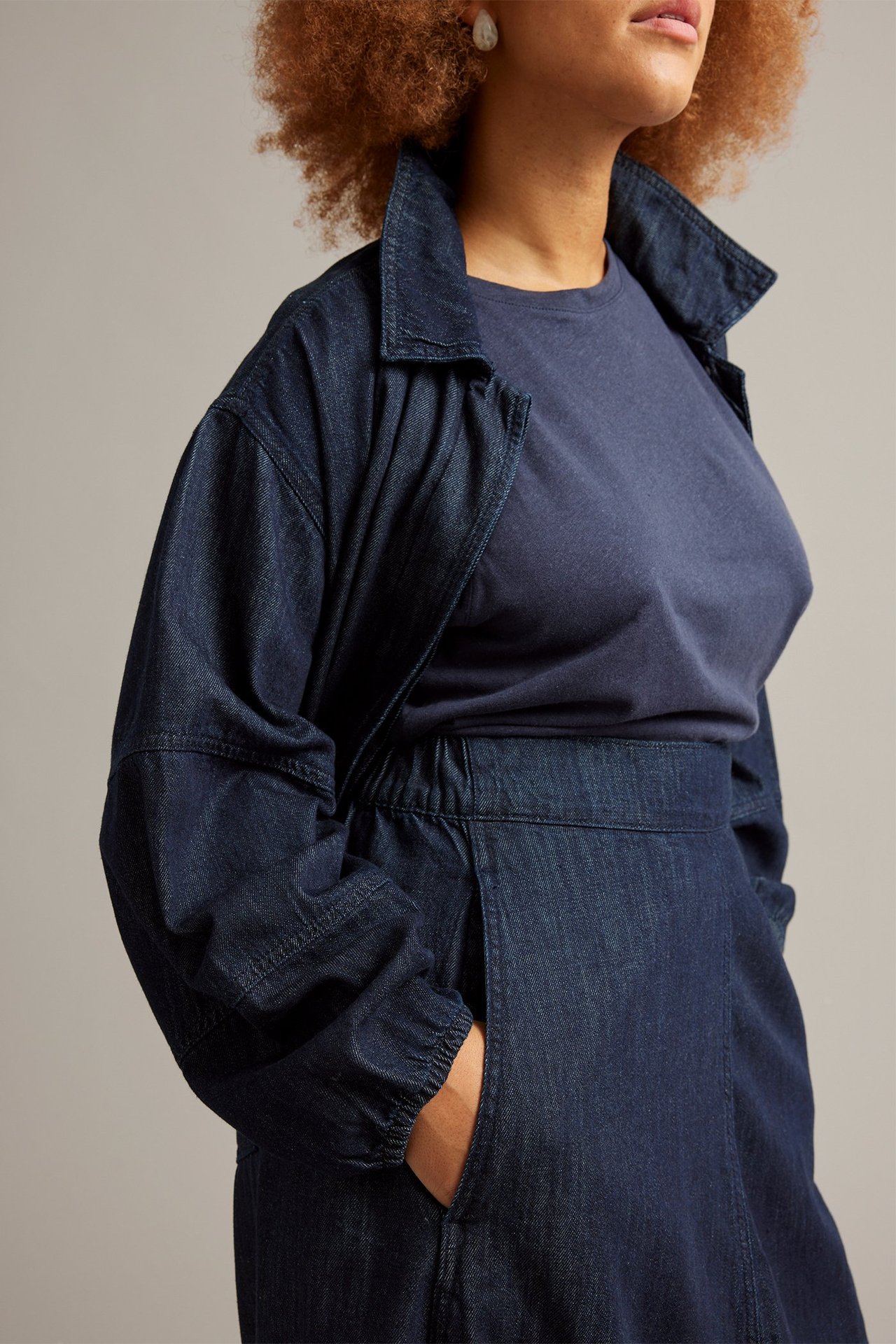 Naisen sivukuva: tumma denim-barrel-hame, yhdistettynä farkkutakkiin ja laivastonsiniseen t-paitaan.