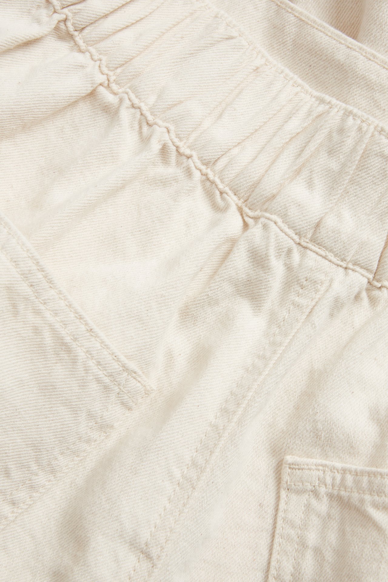 Lähikuva: beigenvärinen denim-barrel-hame, jossa joustava vyötärö ja sivutasku.