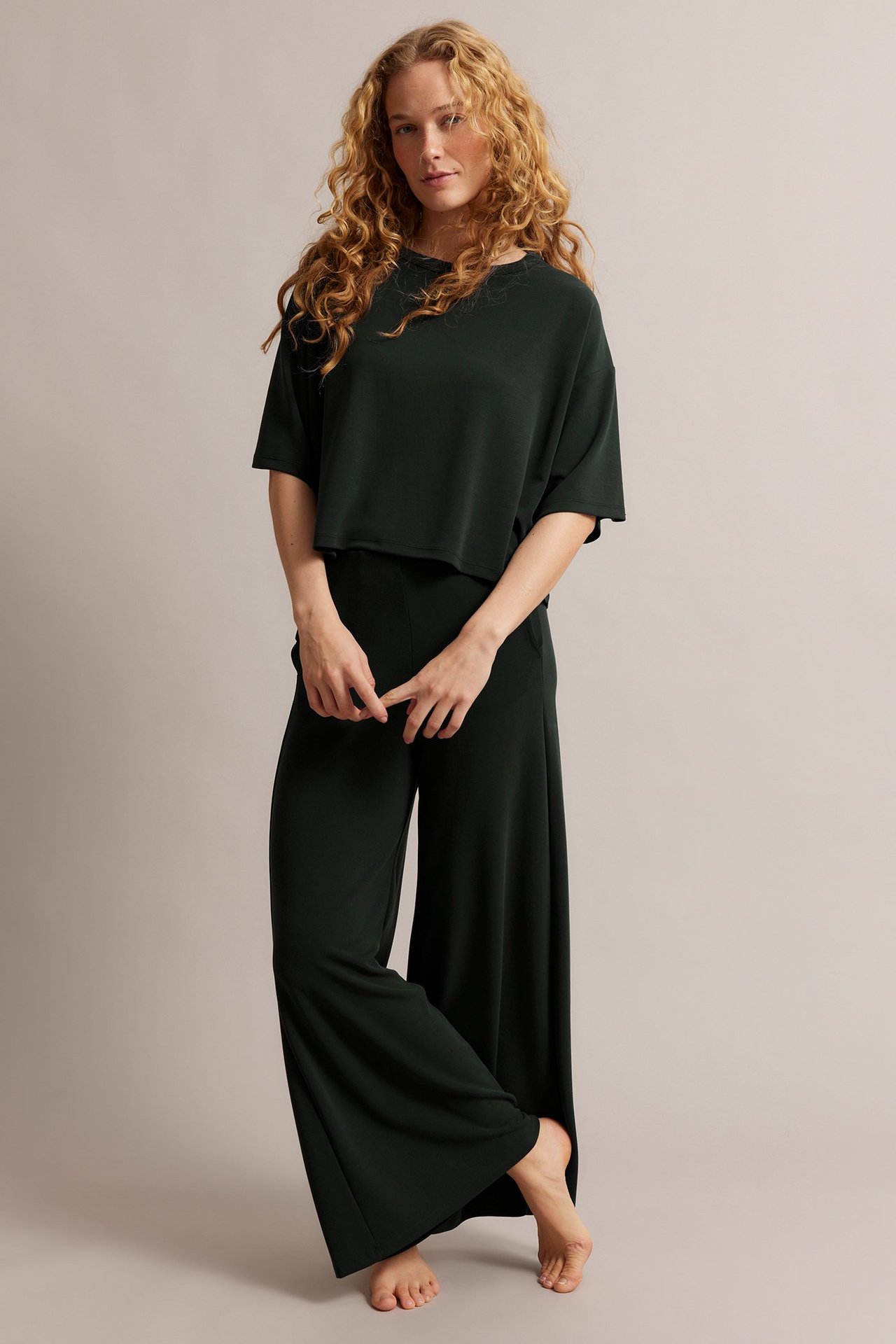 Framifrån: en kvinna i svarta vida loungebyxor och matchande kortärmad, beskuren topp.