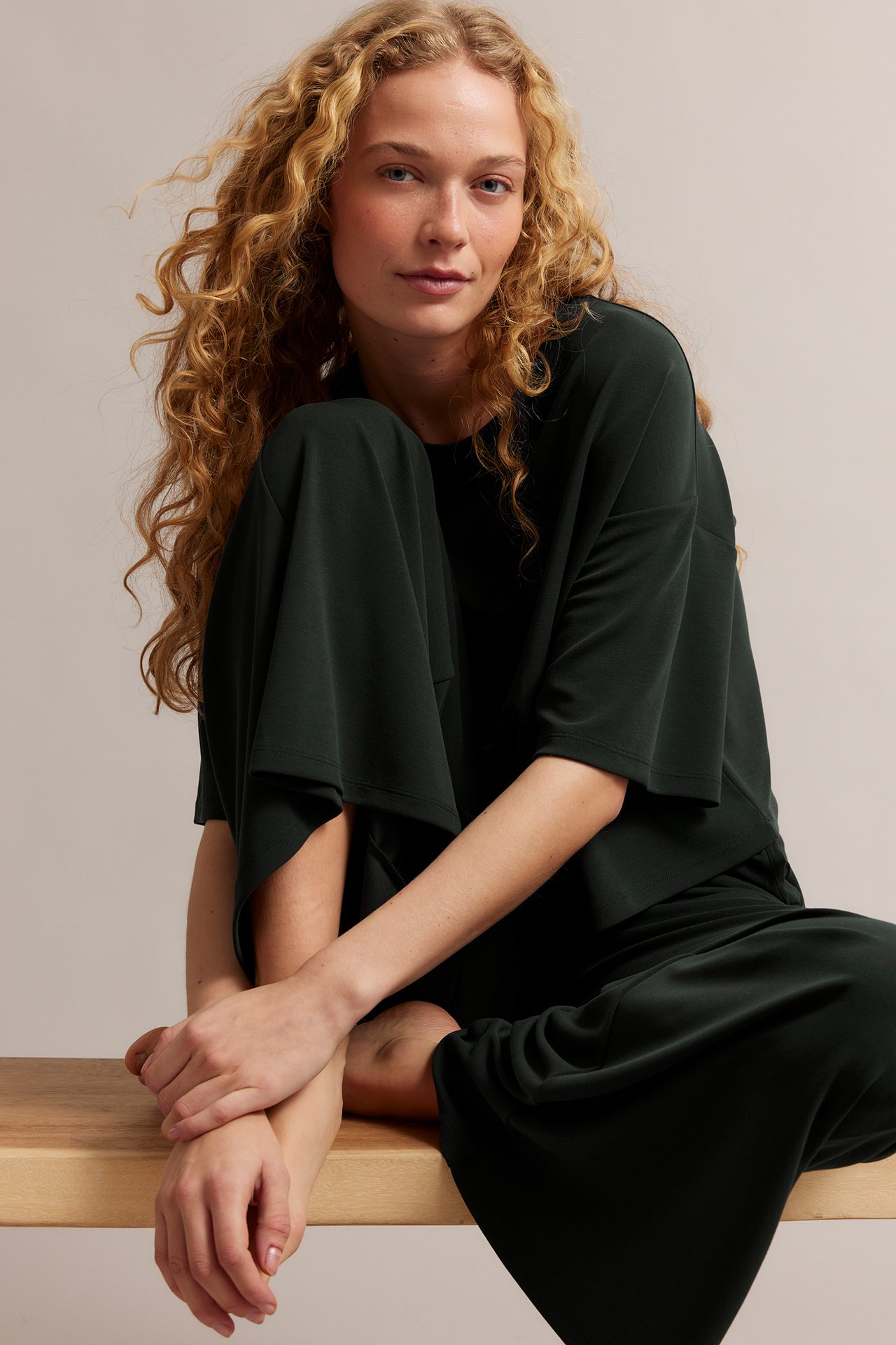 Framsida: Kvinna i svarta lösa loungewearbyxor och matchande kortärmad topp.