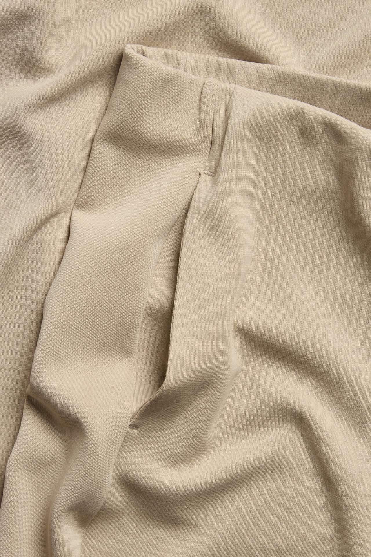 Närbild på en beige loungewearbyxas sidficka i mjuk modalblandning.