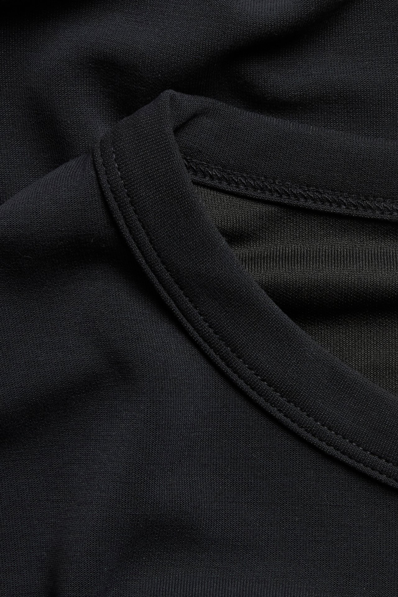 Närbild av en svart T-shirt i modalmix, som visar V-ringningen och tygstrukturen.
