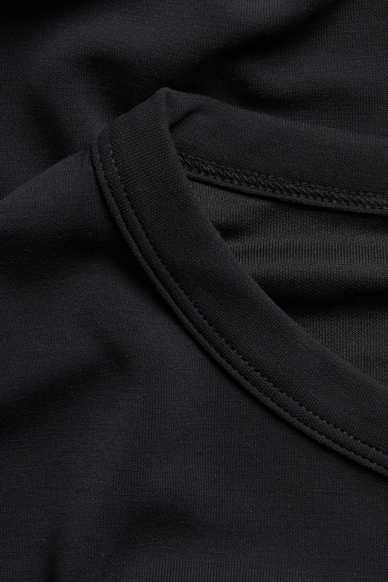 Zbliżenie na czarny T-shirt z domieszką modalu, pokazujące dekolt w serek i fakturę materiału.