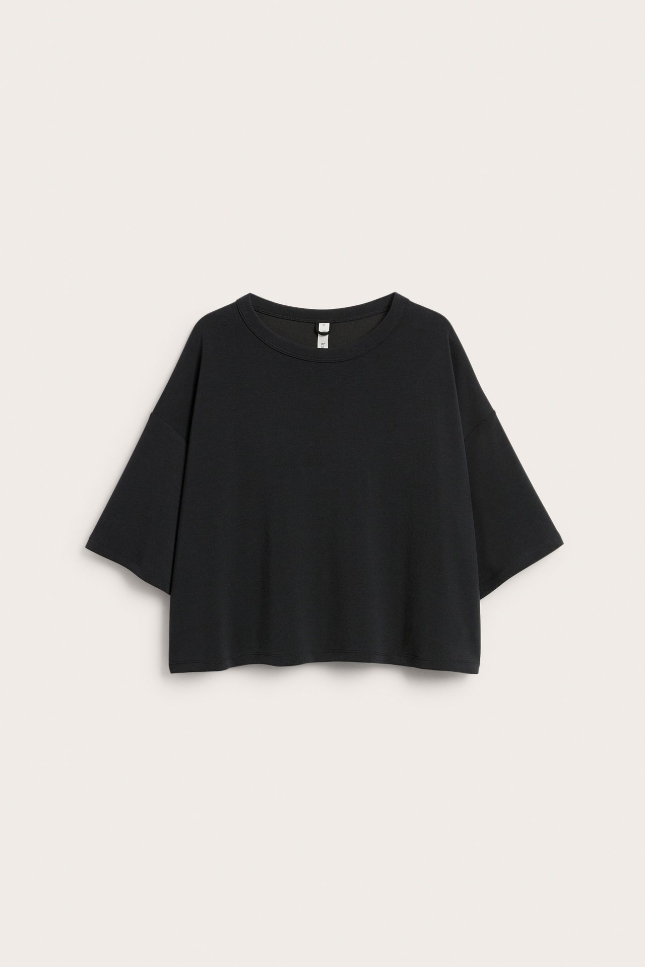 Framifrån svart lös croppad t-shirt med korta ärmar och rund hals.