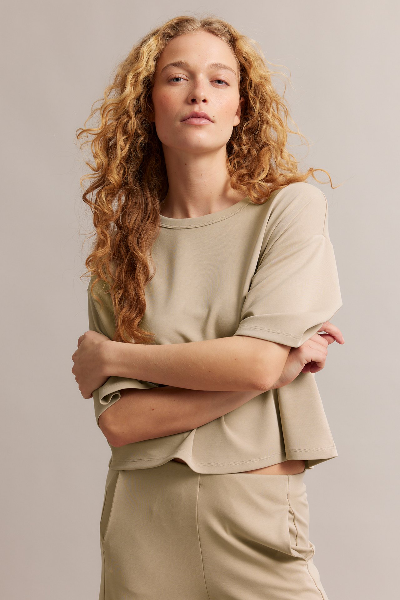 Edestäpäin, nainen yllään beige, laatikkomainen modaalisekoite t-paita ja beiget housut.