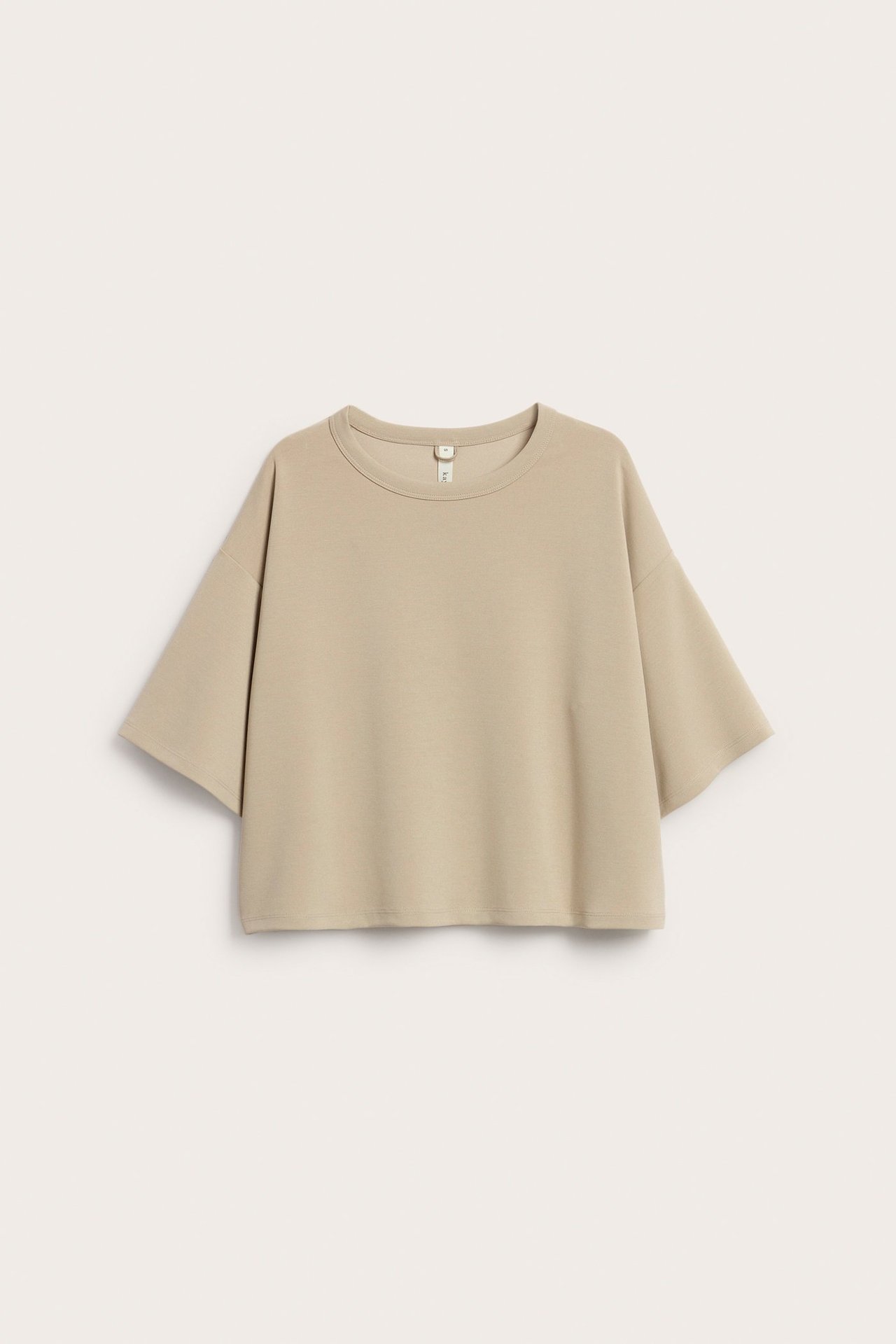 Widok z przodu beżowej, jednolitej, luźnej koszulki T-shirt z miękkiej mieszanki modalu, ułożonej płasko.