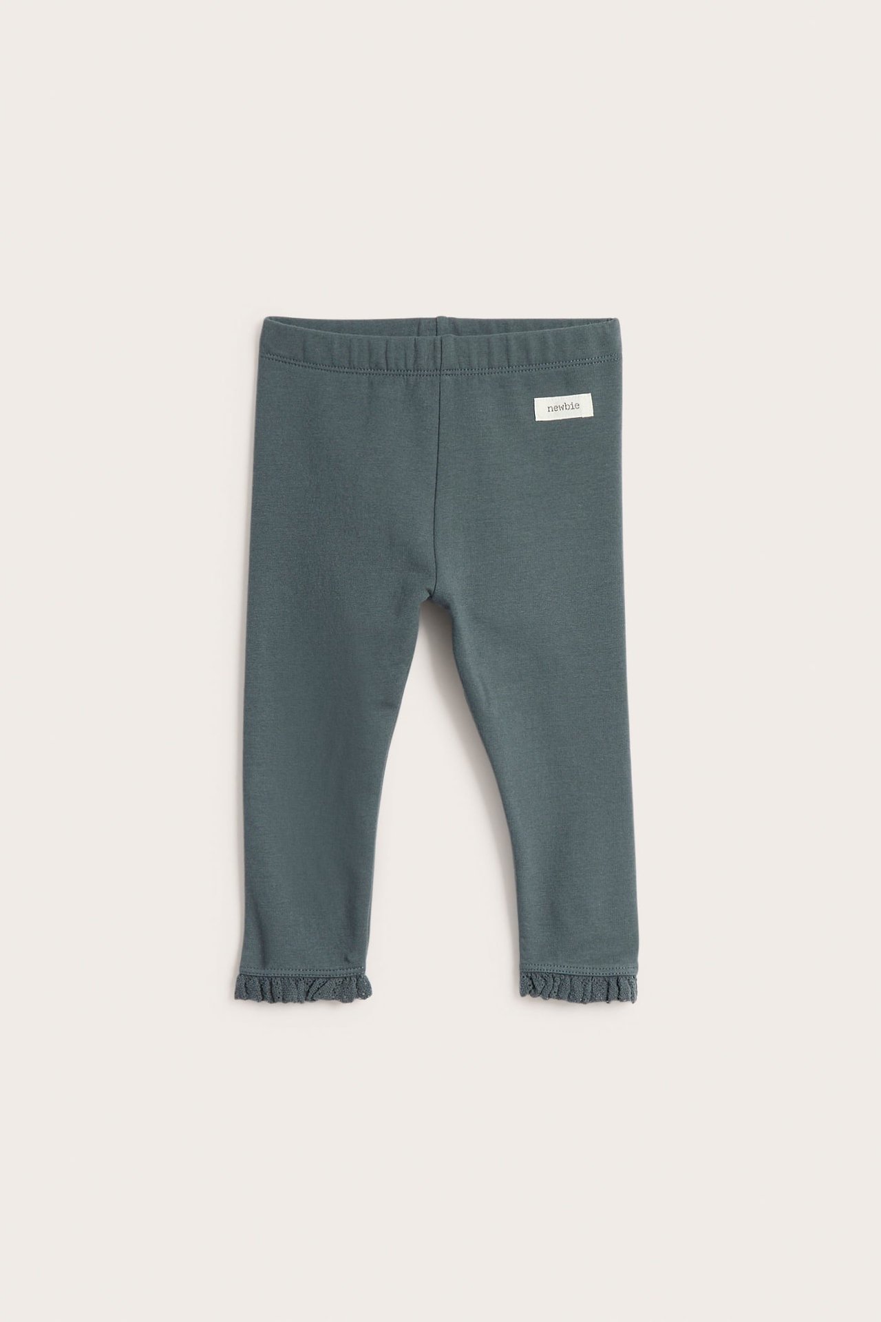 Edestäpäin kuvatut vauvan tumman turkoosit jerseyleggingsit röyhelöreunoilla.