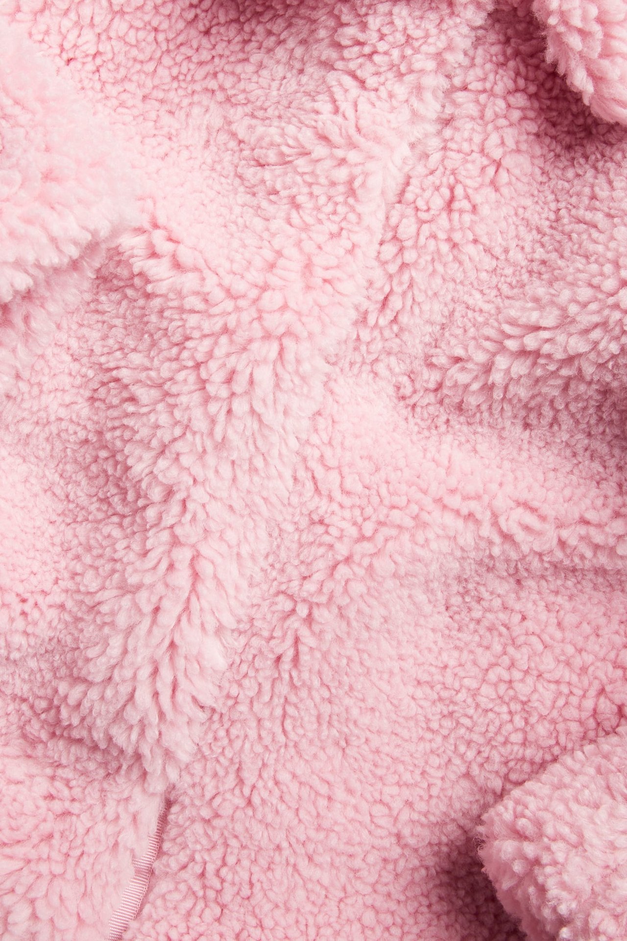 Närbild på rosa lurvigt fleecetyg med mjuk textur.