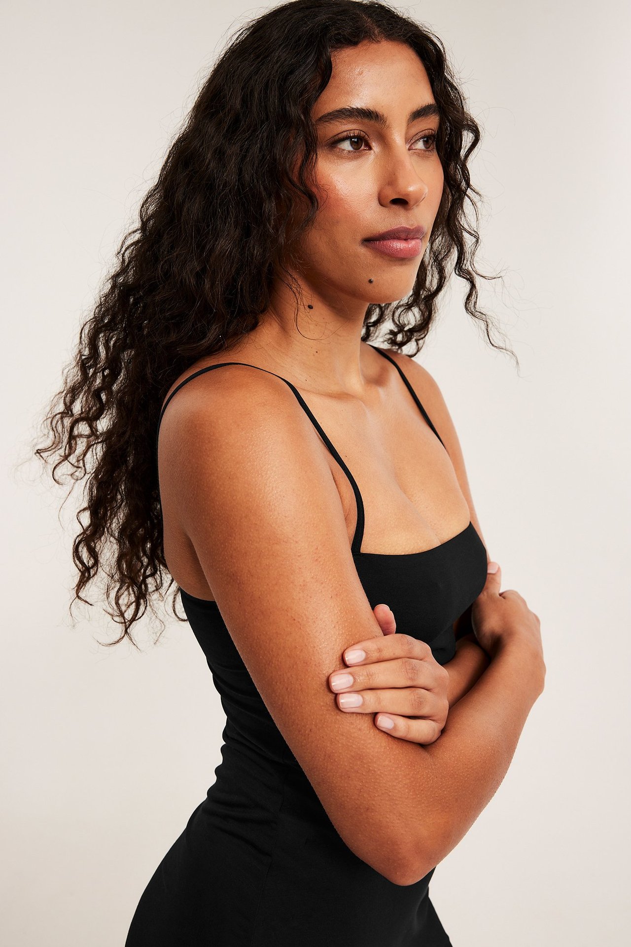 Nærbilde, sidevisning av kvinne i svart modalmix underkjole med tynne justerbare skulderstropper.