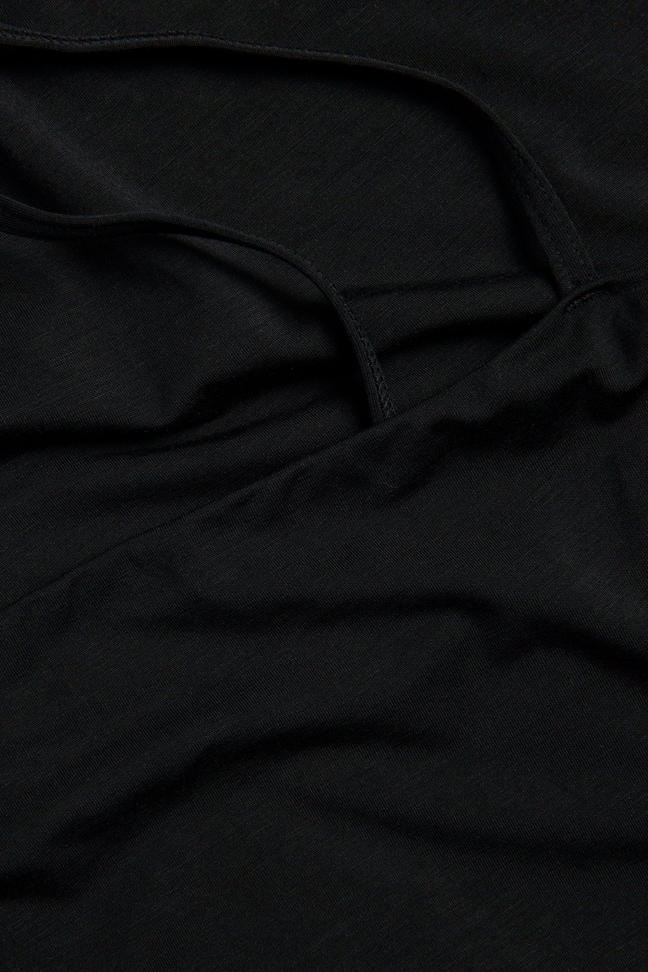 Närbild på en svart enfärgad underklänning i lyocellmix med synliga justerbara axelband.