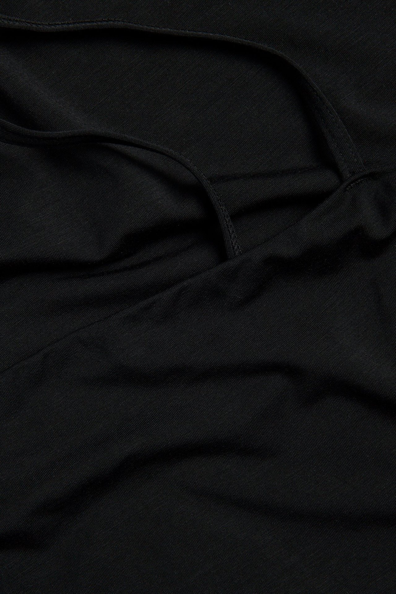 Närbild på en svart enfärgad underklänning i lyocellmix med synliga justerbara axelband.