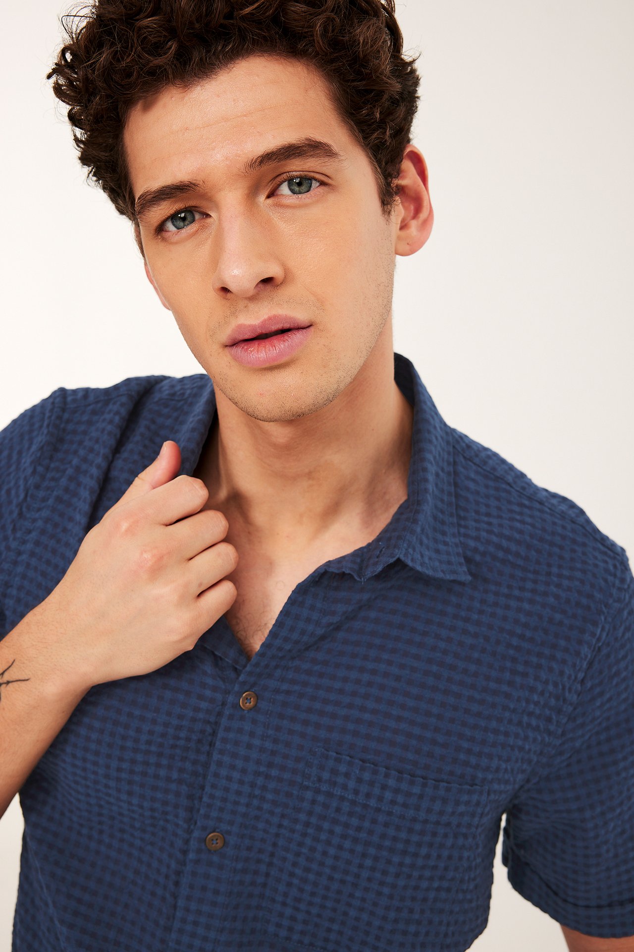 Närbild framifrån på en man i en blårutig kortärmad bomullsskjorta med bröstficka.